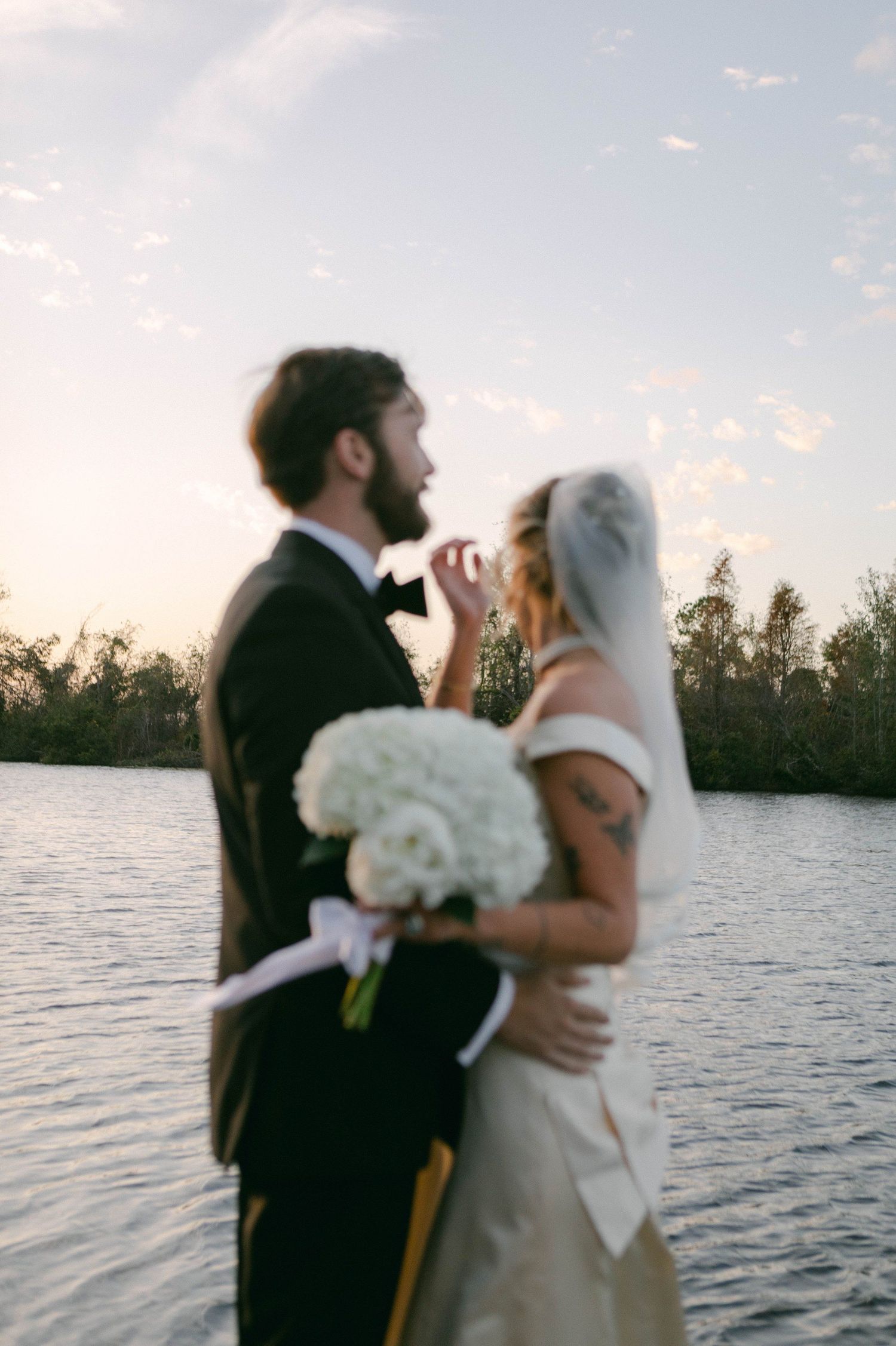 Romantic sunset beach wedding photos with couple embracing by the water.