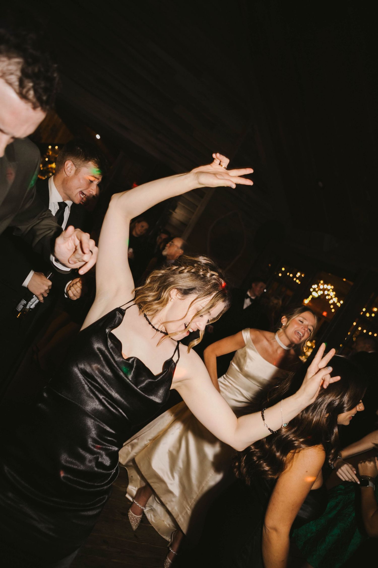Wedding reception dancers move energetically on a dark dance floor.