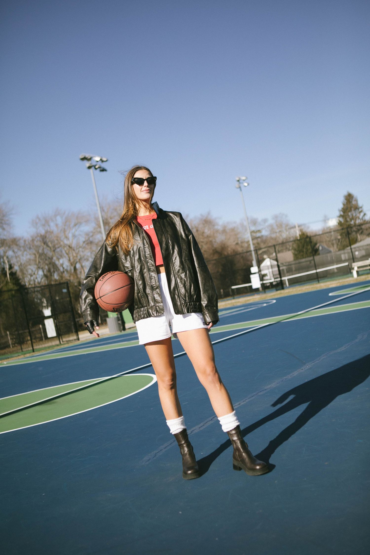 Stylish basketball court fashion shot with leather jacket and boots.
