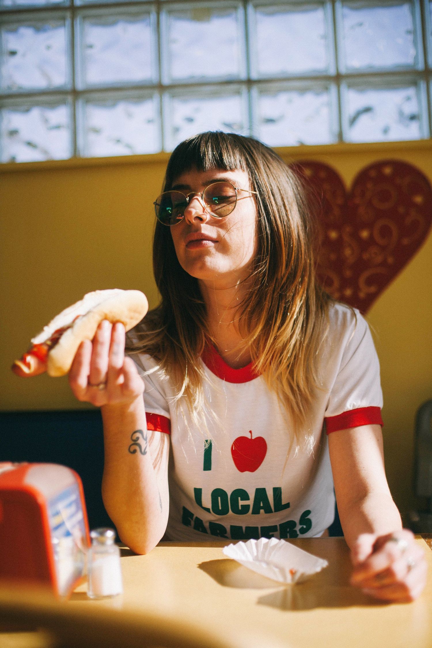 Person wearing Local graphic t-shirt sitting at table in casual indoor setting.