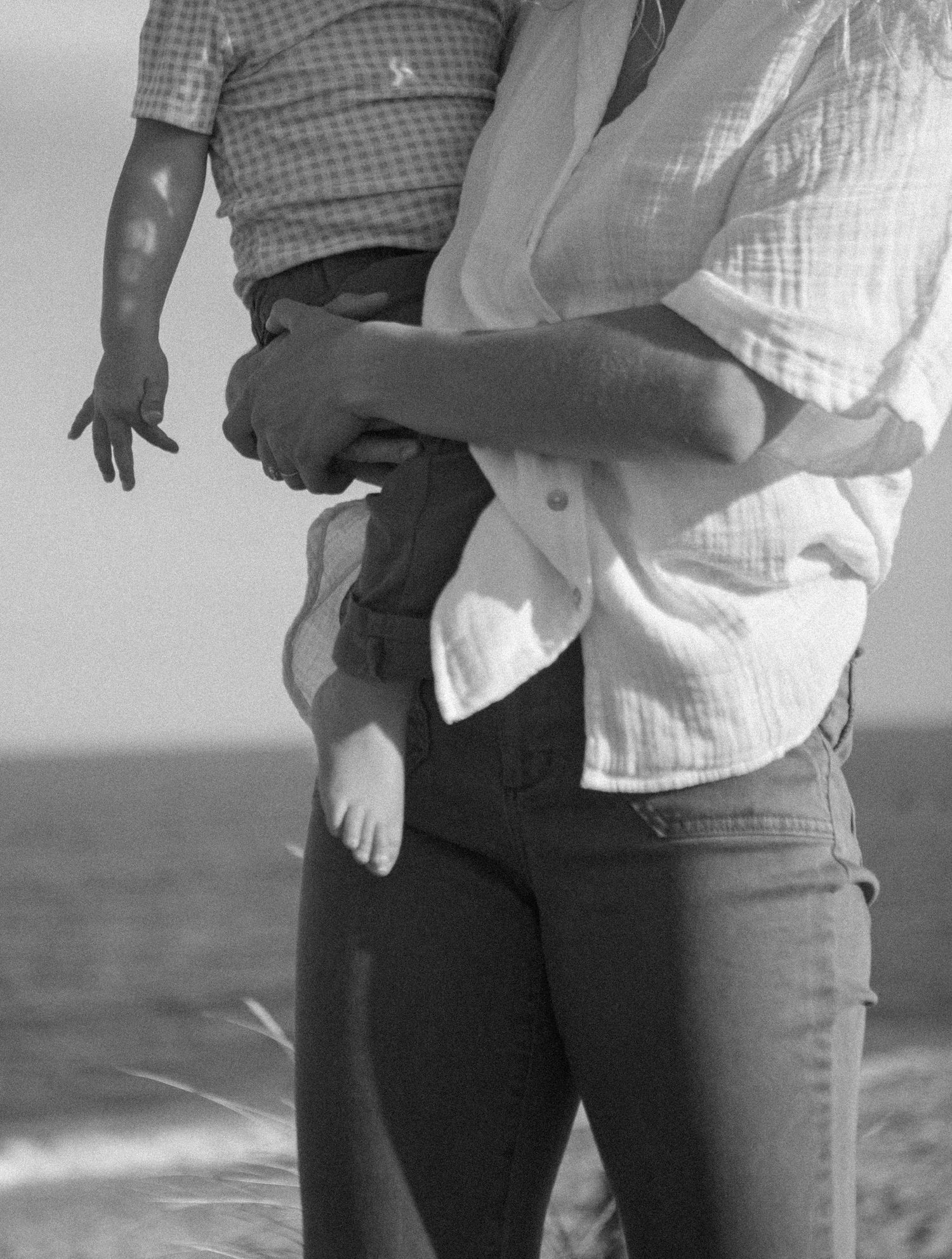 Two people standing close together against an ocean backdrop.