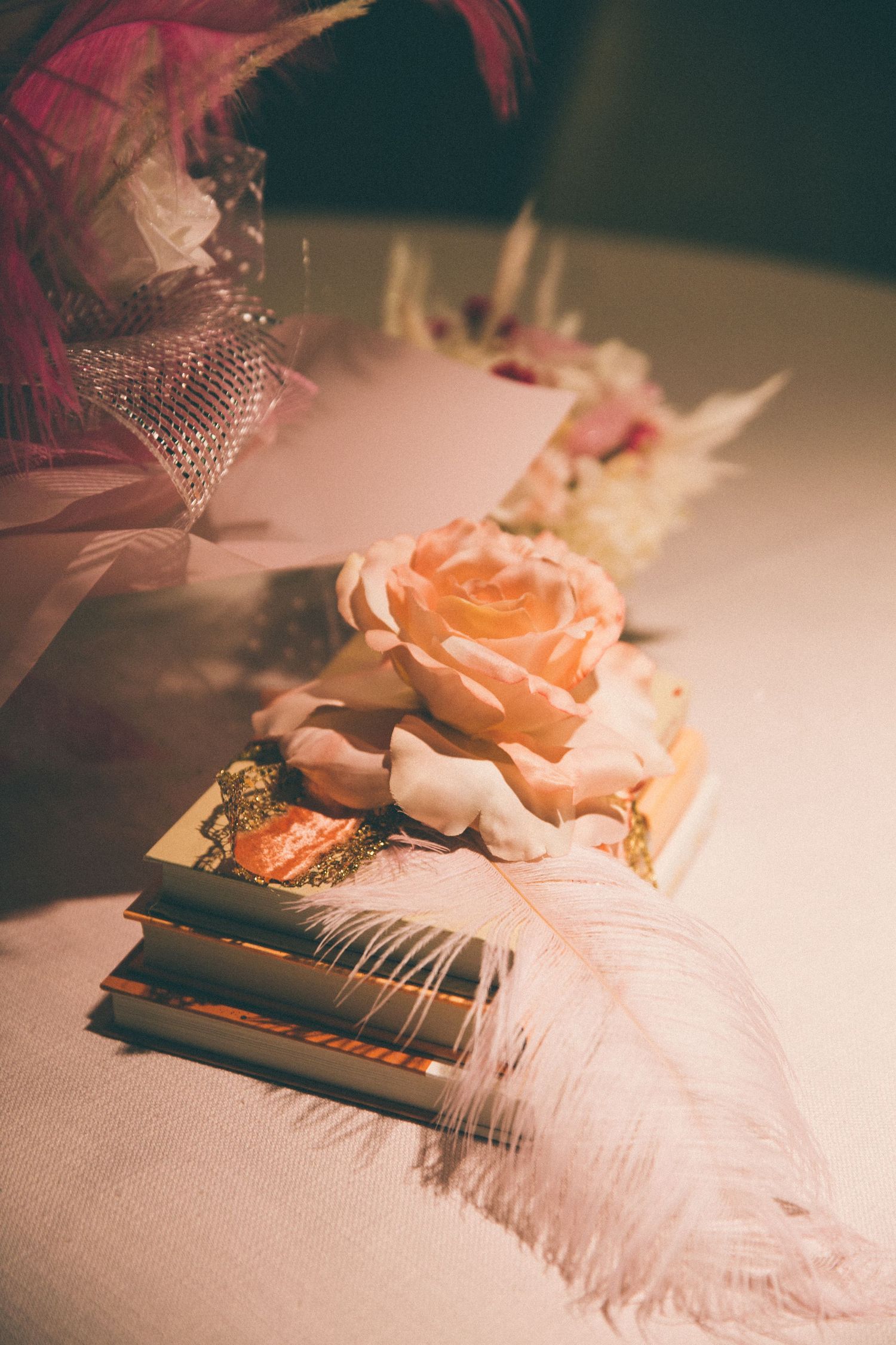 Vintage style arrangement with pink rose, feathers and decorative elements.