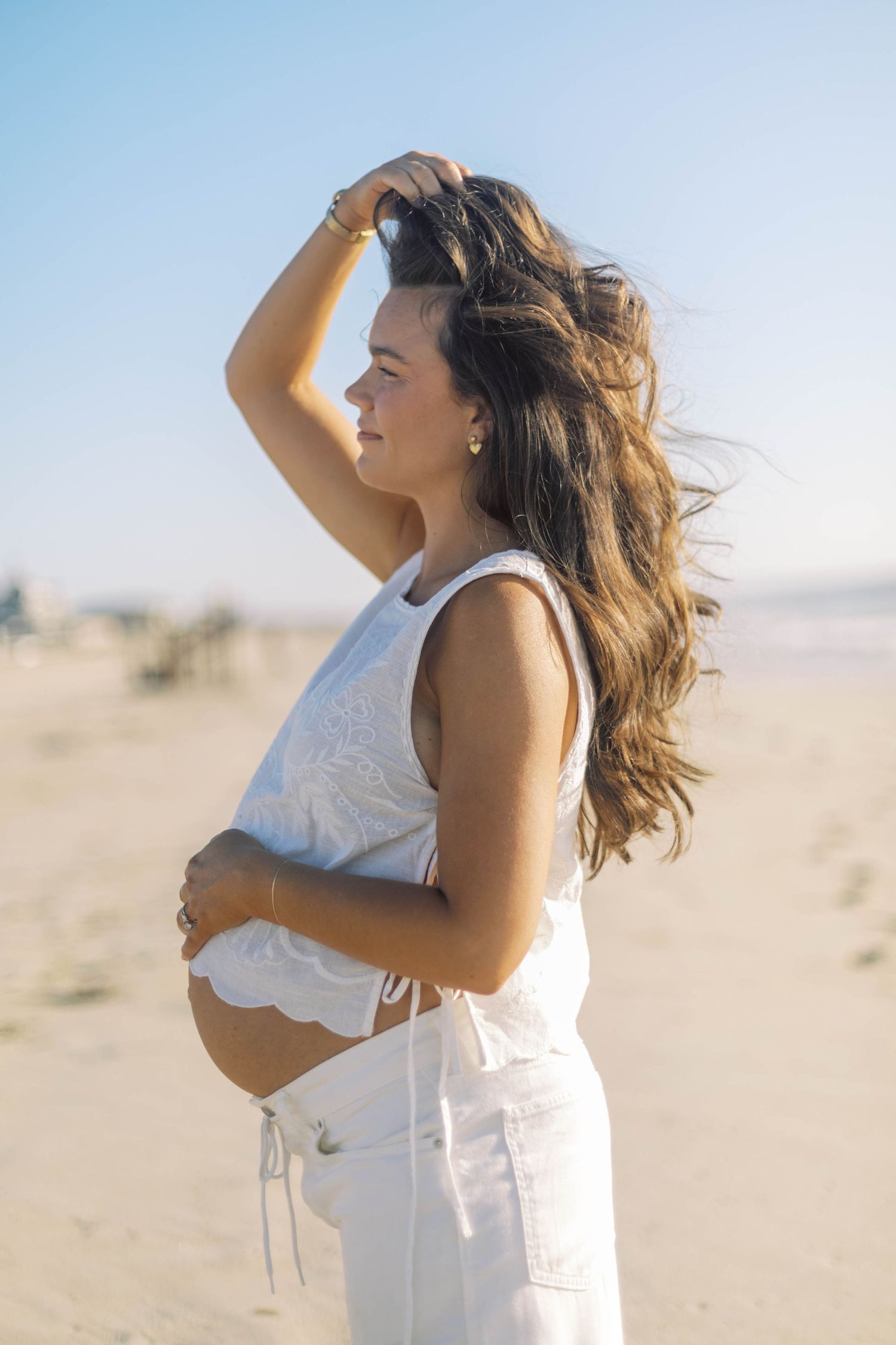 Woman in white dress posing against desert landscape with windswept hair.