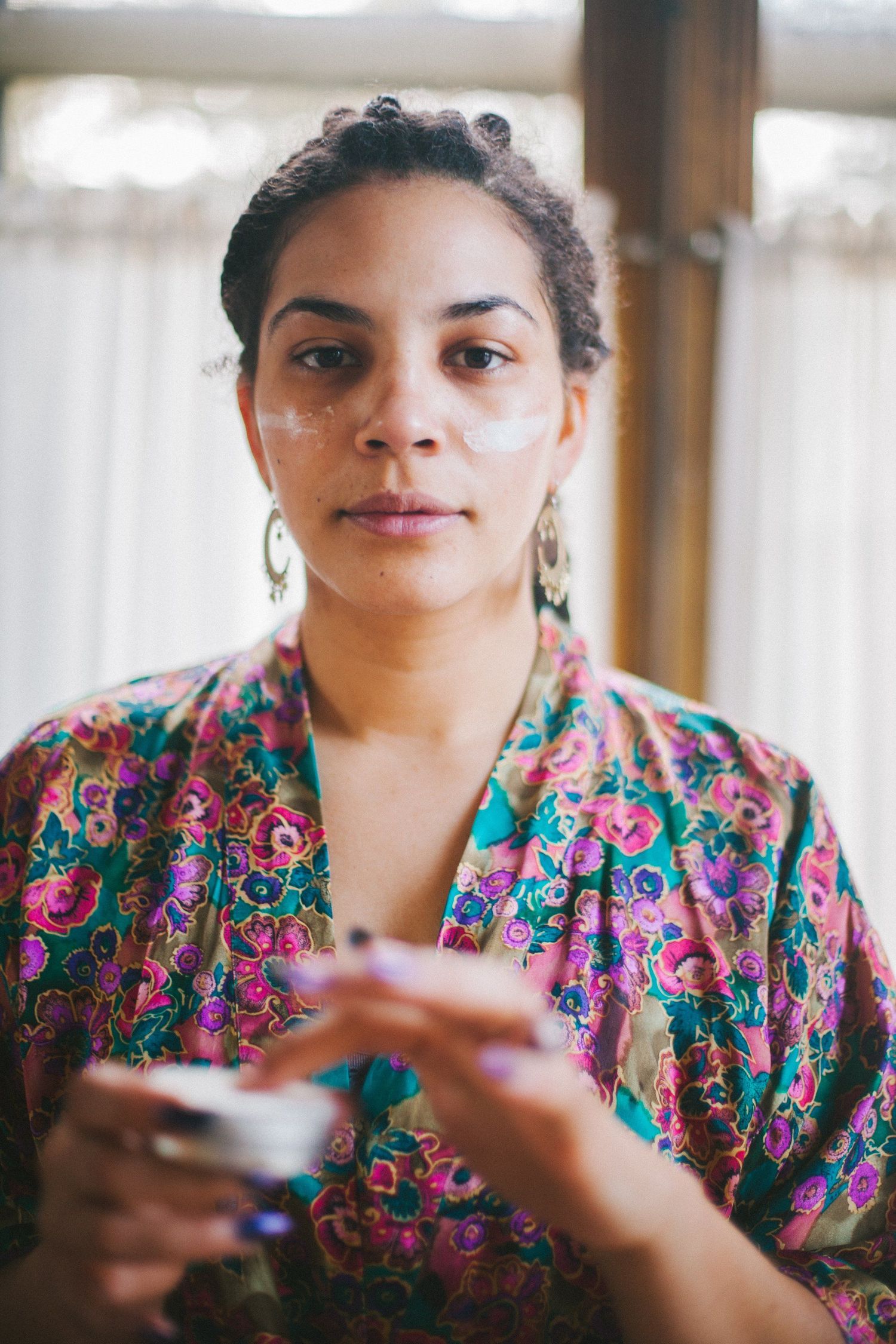 Person wearing colorful floral print dress holding something in their hands.