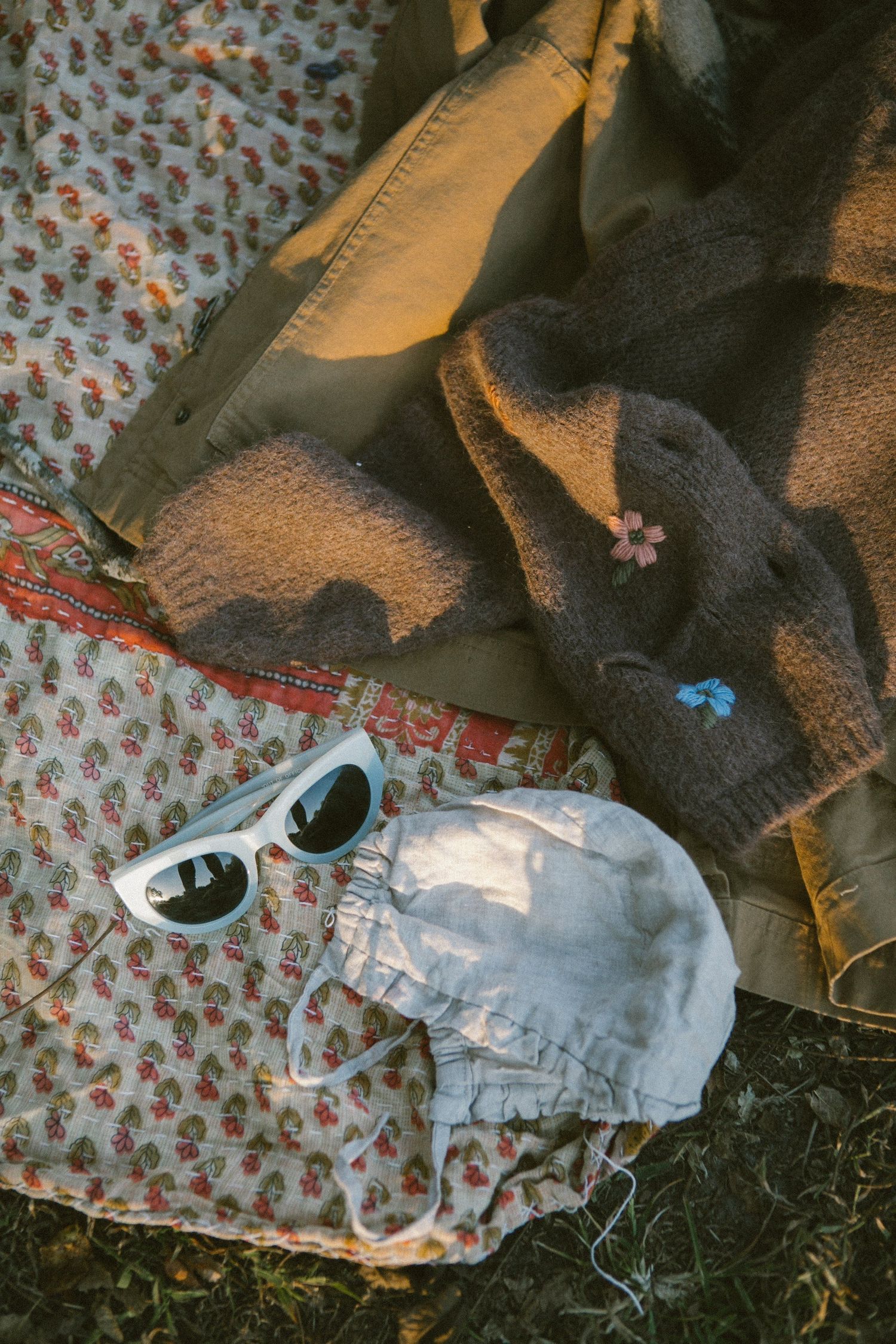 Vintage clothing and accessories arranged on floral patterned fabric.