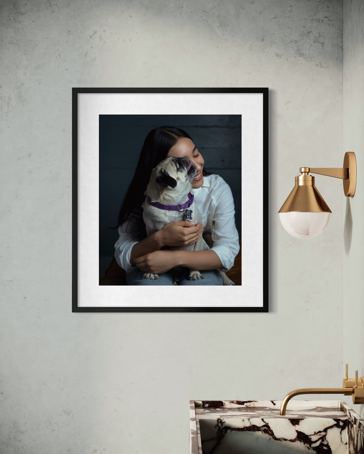 A modern bedroom interior with framed artwork and copper wall sconce against a concrete wall.