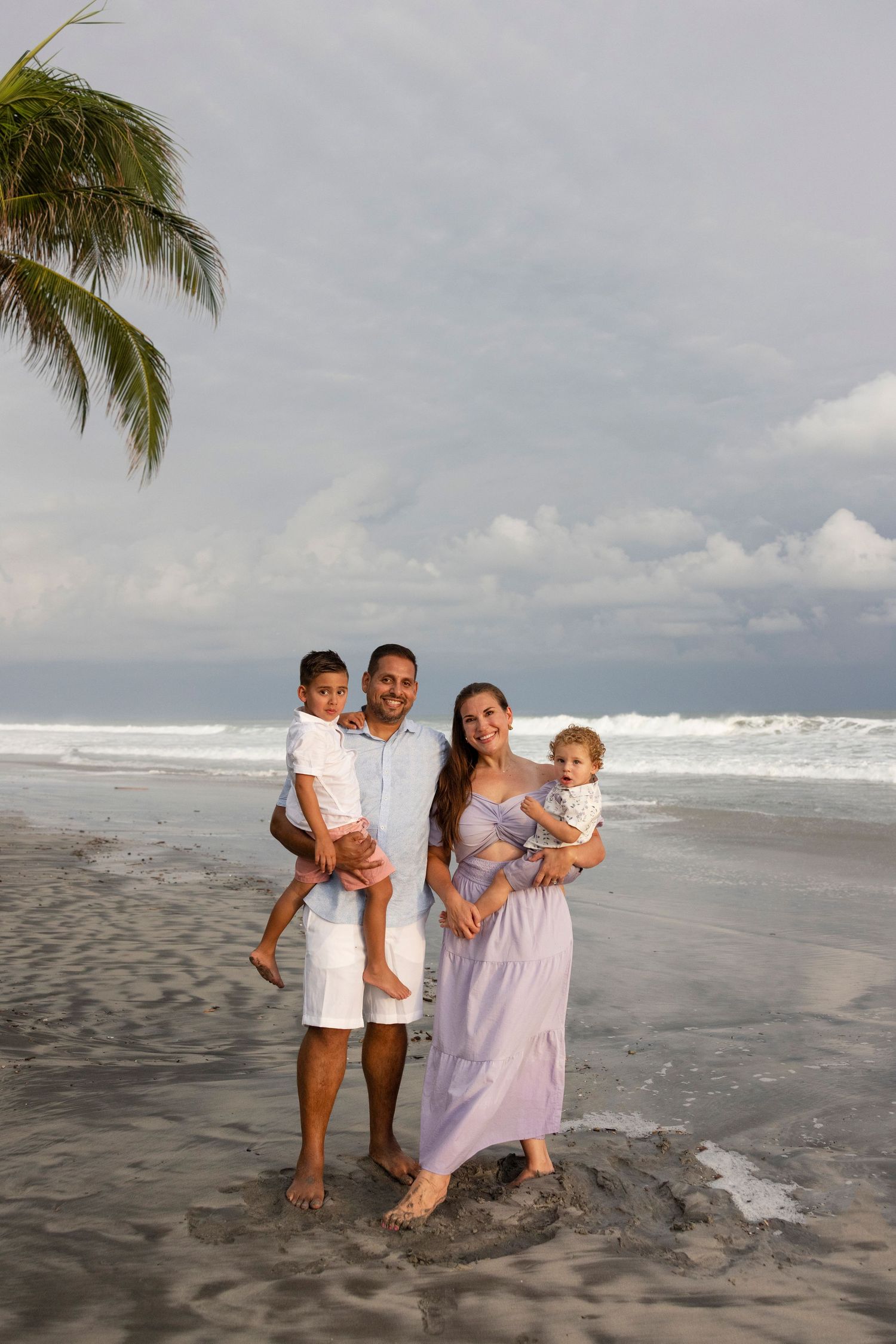 Family beach photography session at Los Veneros in Punta de Mita, Mexico, capturing parents and their child beneath the palm trees.