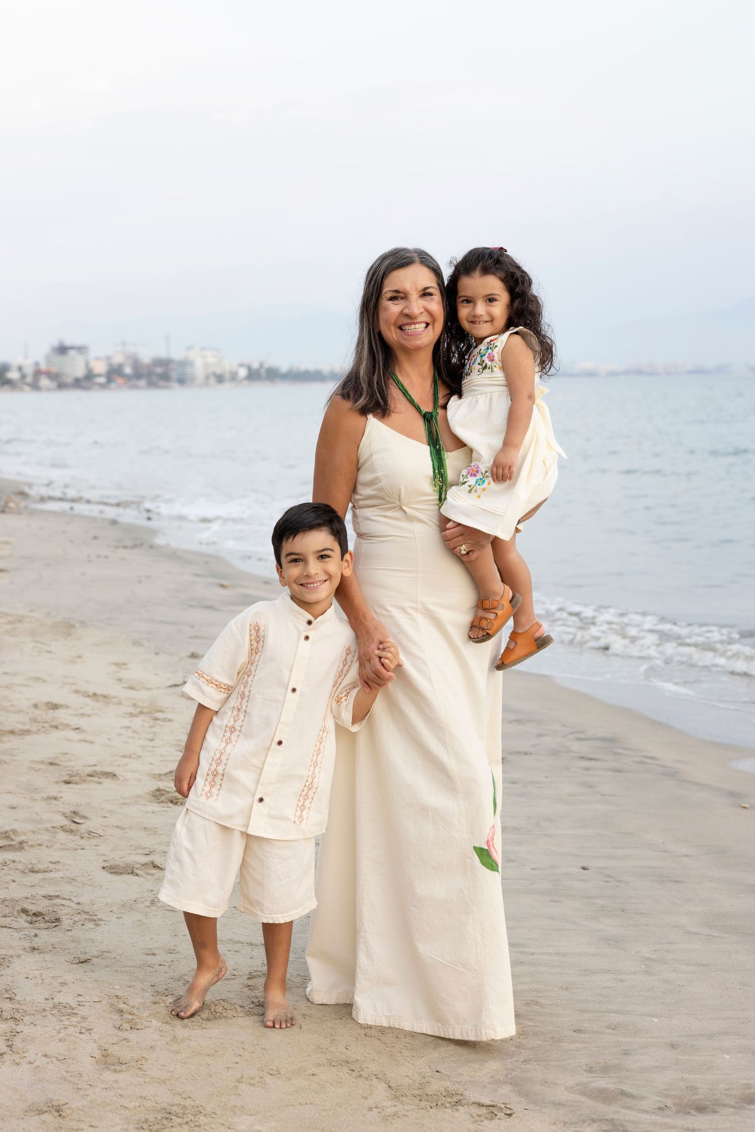 Family beach photography session in Bucerías, Mexico, capturing a mother and her children together along the shore.