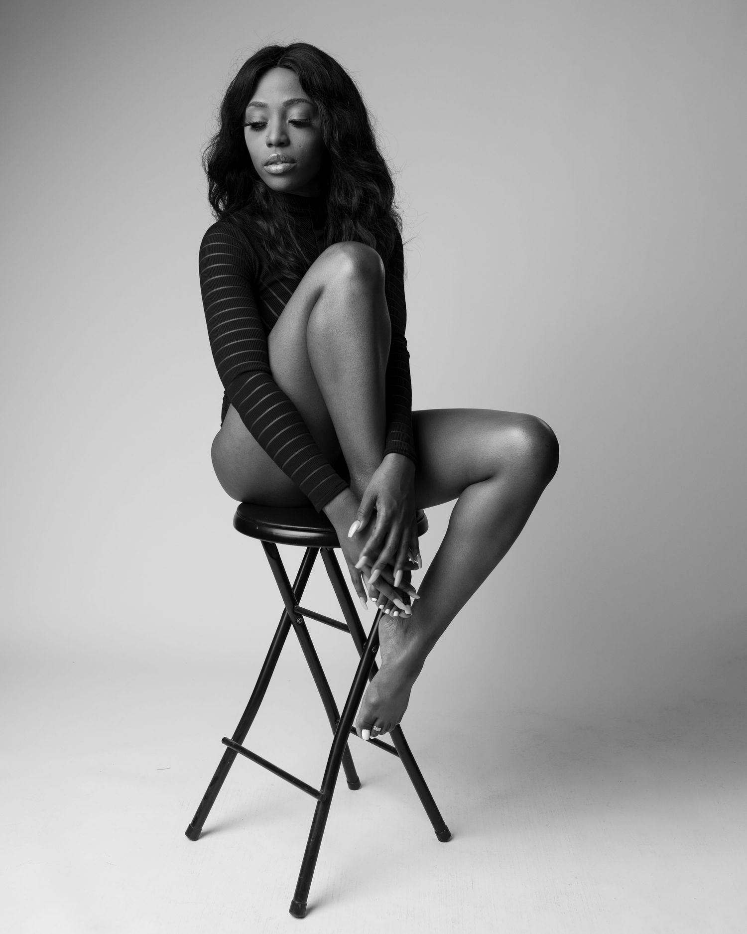 female sitting on chair with one leg up. black and white