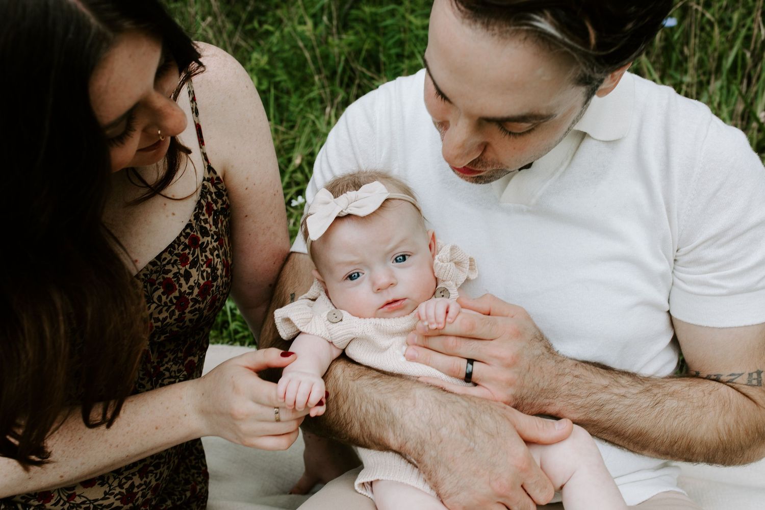 Intimate family moment outdoors with baby in pink outfit.
