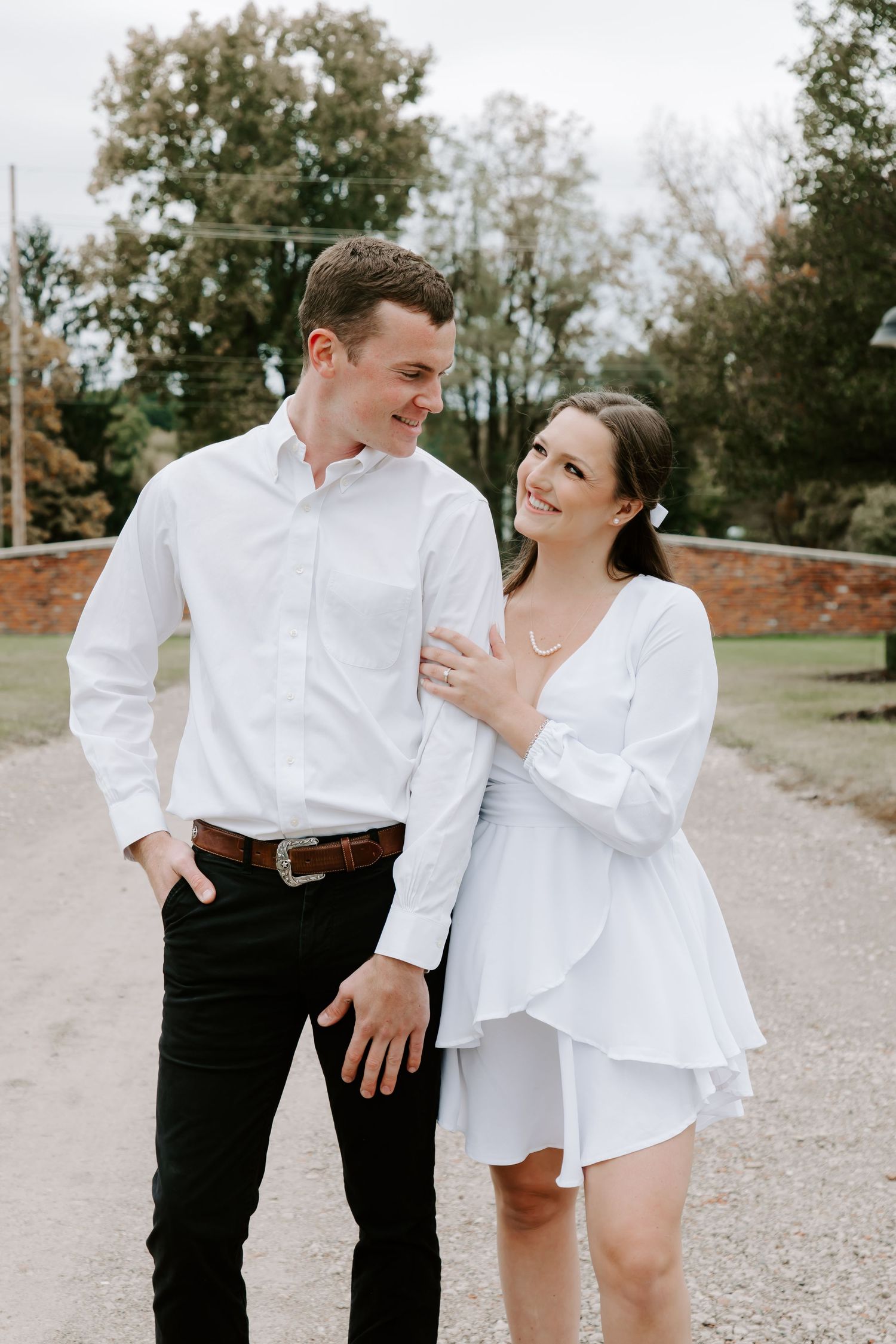 Couple sharing a candid moment on a pathway in front of lush greenery.