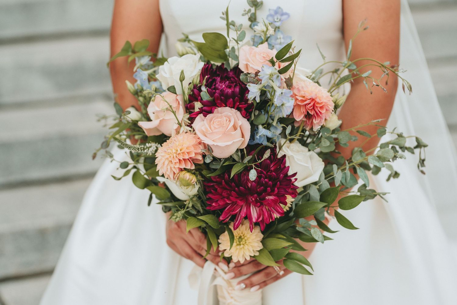 Wedding bouquets featuring pink and burgundy flowers with greenery arranged in a row.
