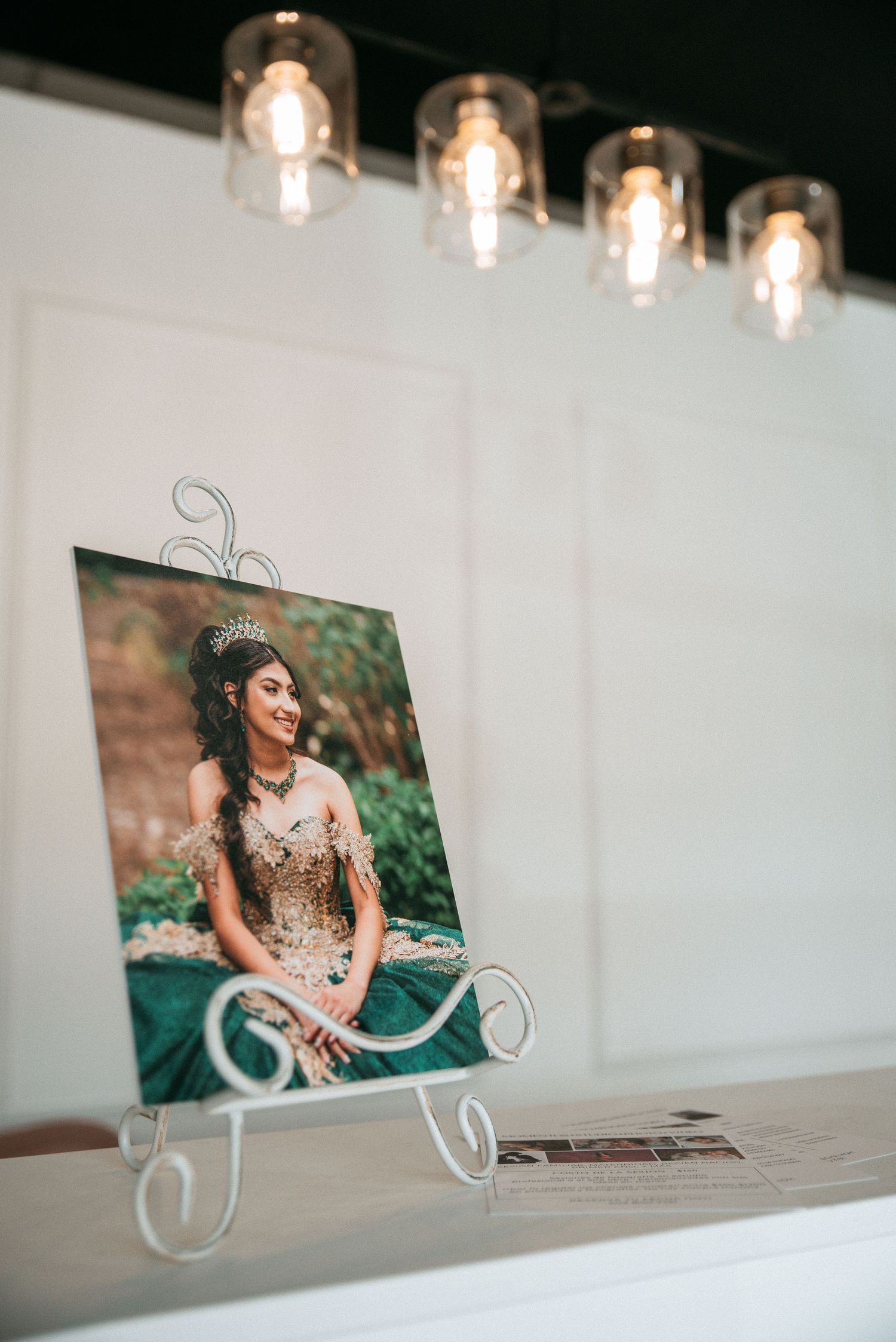 A framed portrait sits on display under modern pendant lights with decorative metal stand.