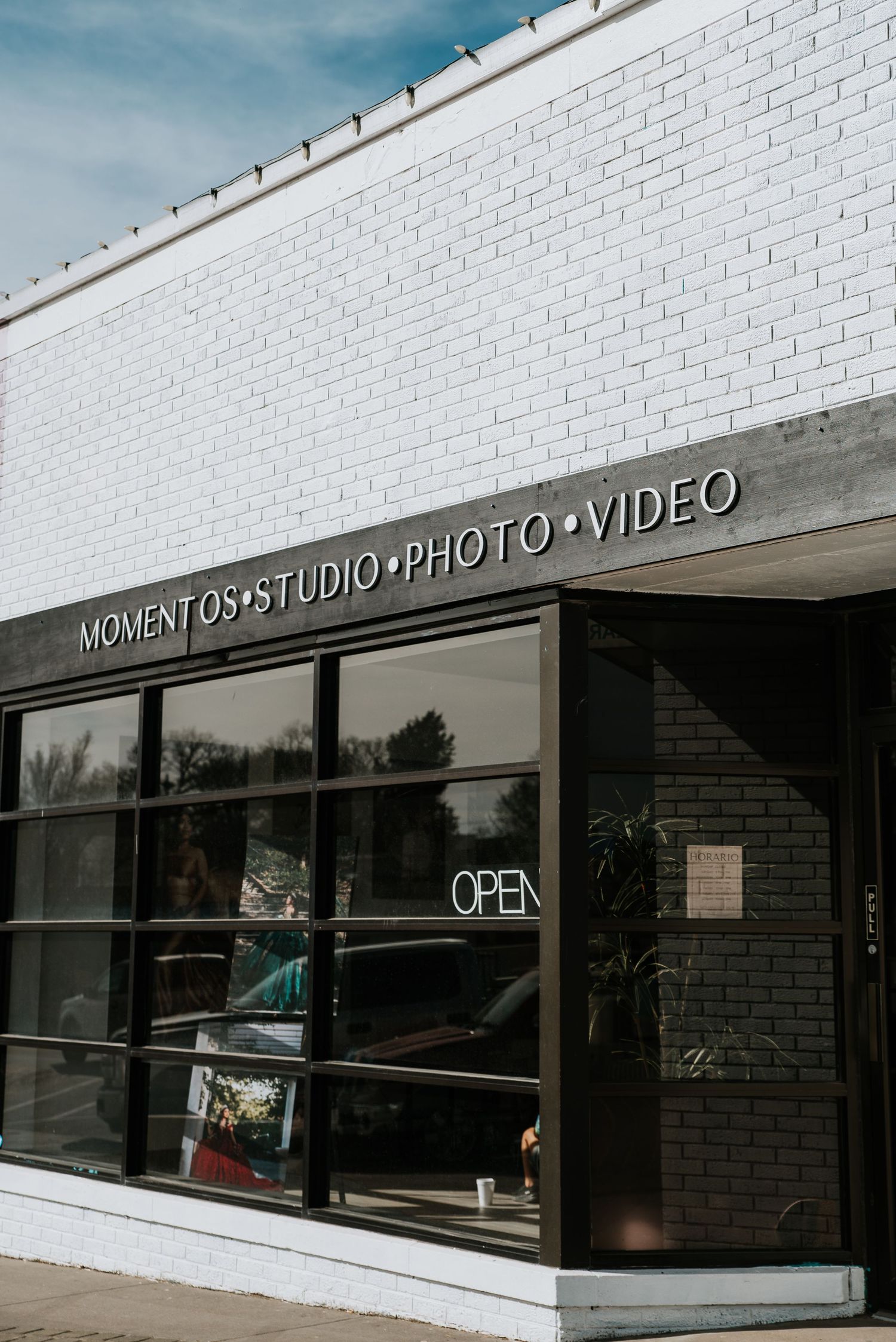 Exterior view of a photography studio storefront with white brick walls and black signage displaying 'Photo Video' text.