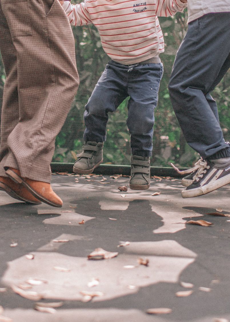 Five sequential photos show feet walking in a line formation on a concrete path with fallen autumn leaves.