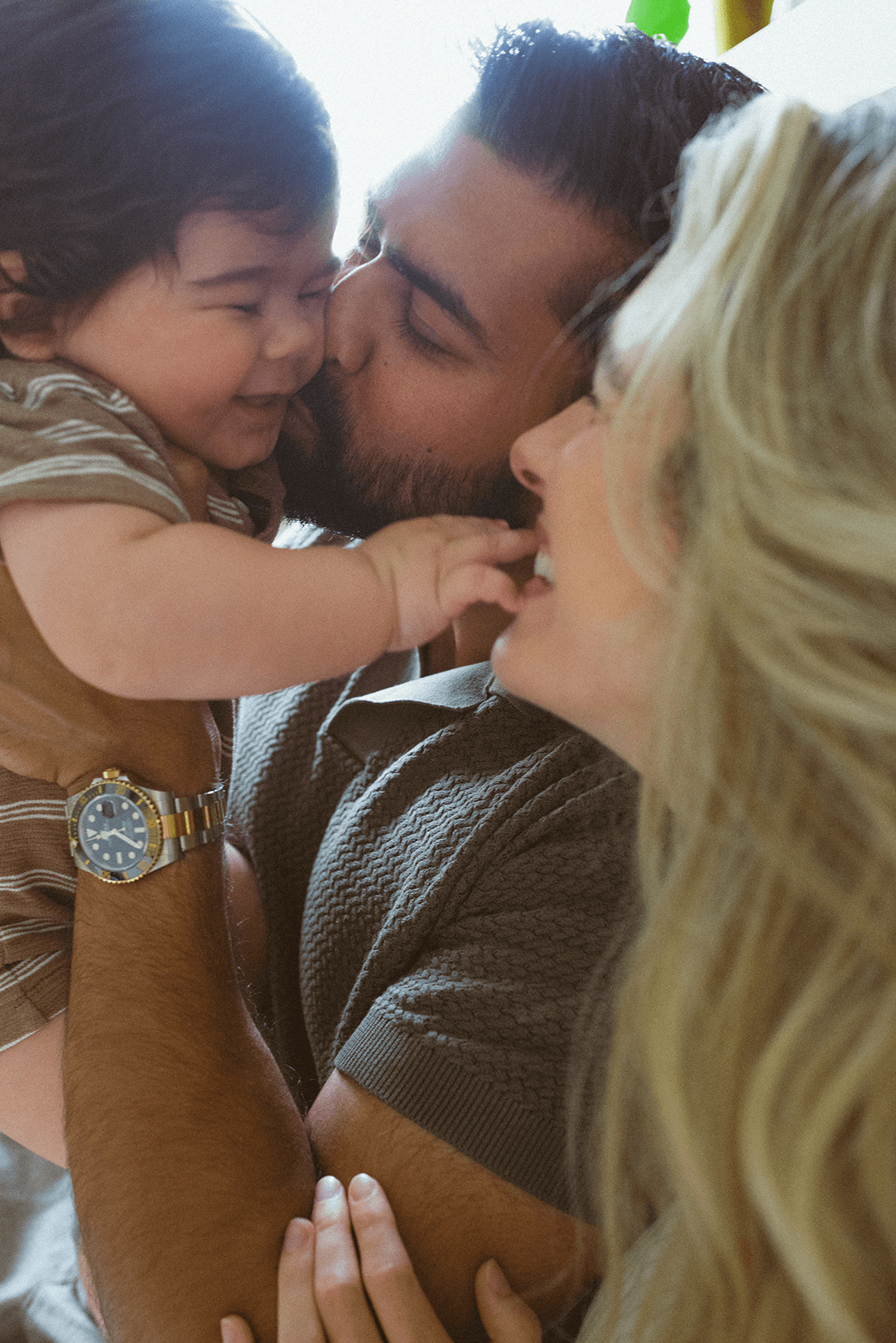 A loving family shares an intimate moment together, with warm lighting and close physical affection.