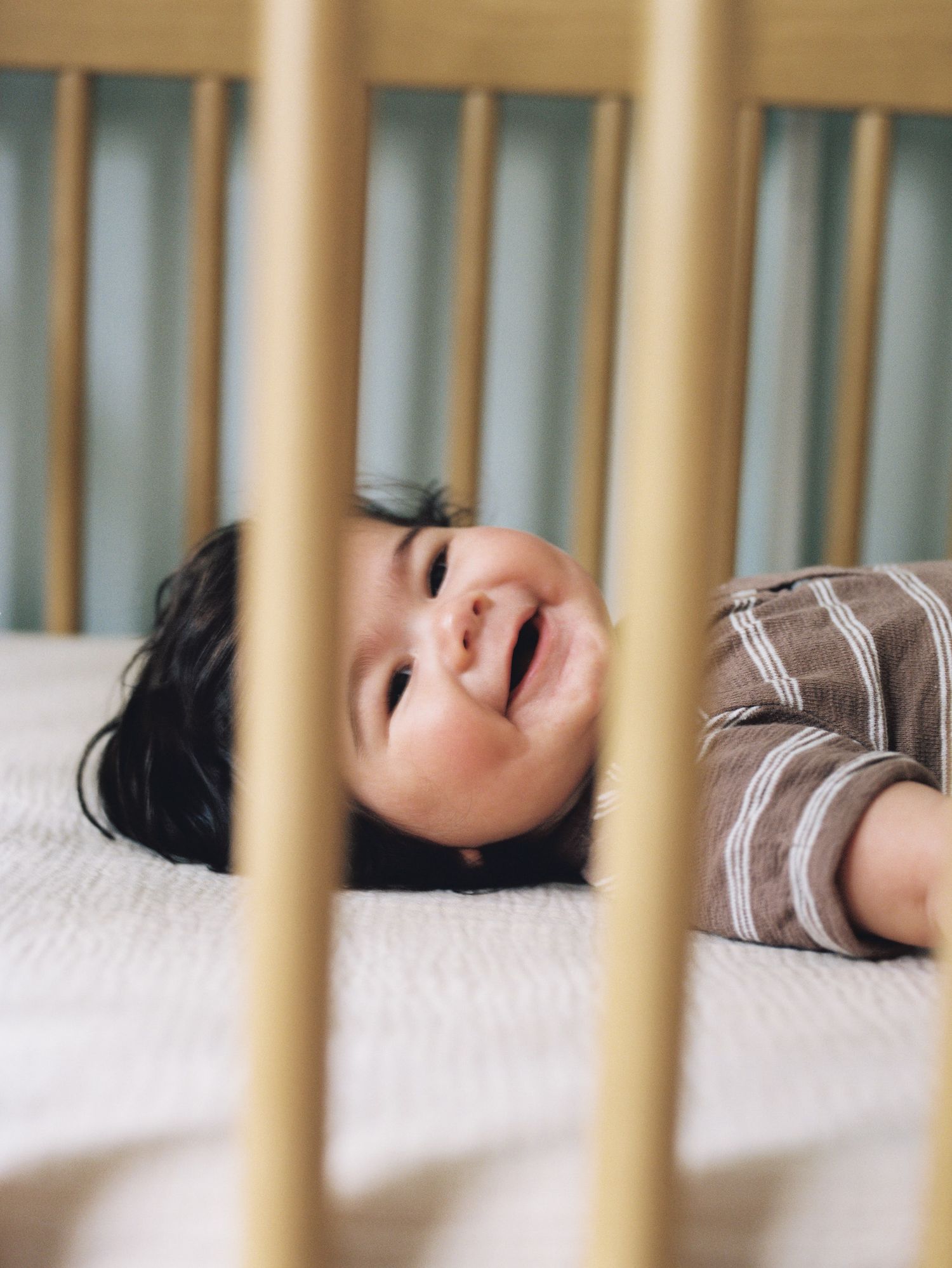 A peaceful sleeping baby rests in a wooden crib with white bedding.