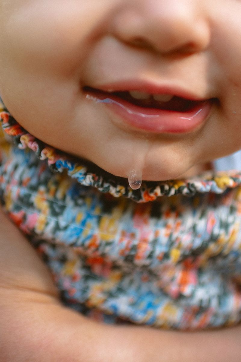 Close-up macro photograph of a drooling mouth wearing a colorful patterned scarf.