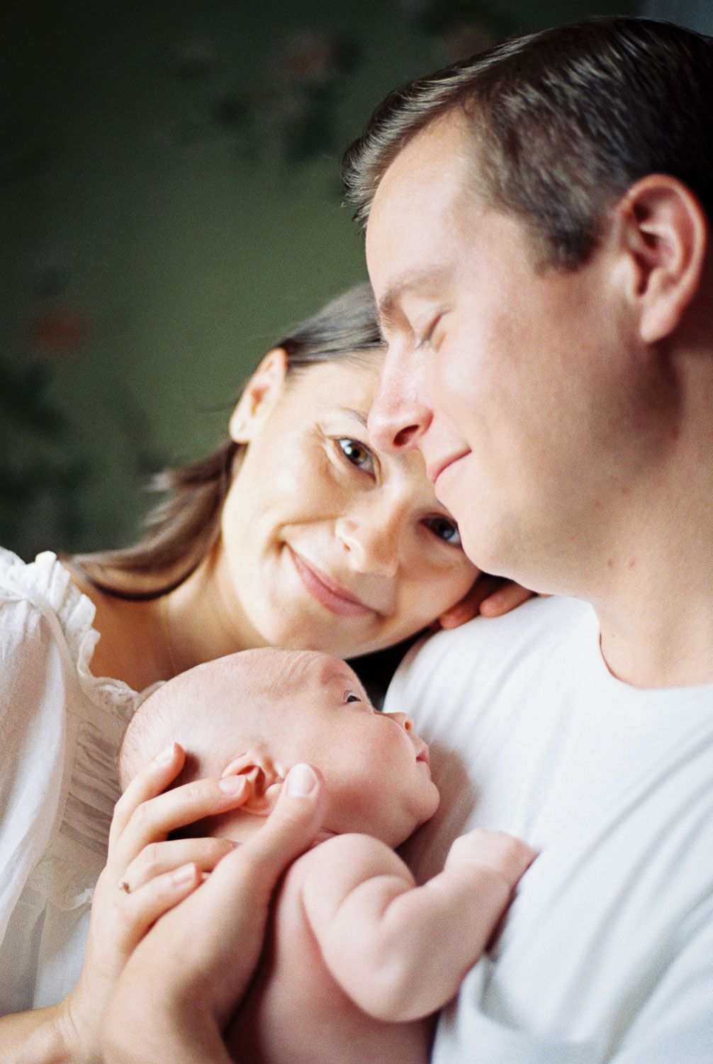 Happy parents smiling at their newborn baby, a tender family portrait capturing a precious first moment together.