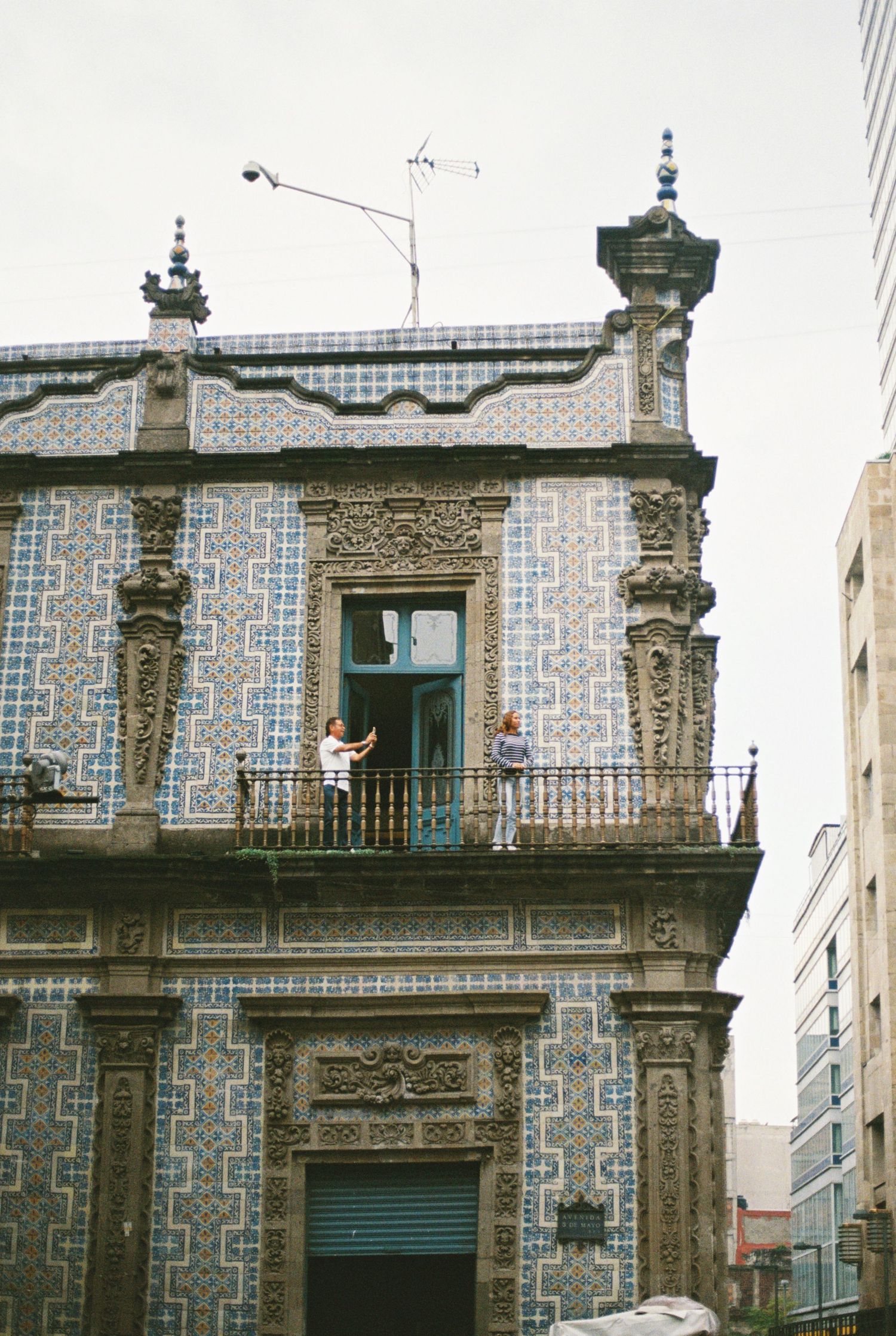 Historic building facade with ornate stonework and blue-and-white decorative tiles in a geometric pattern.