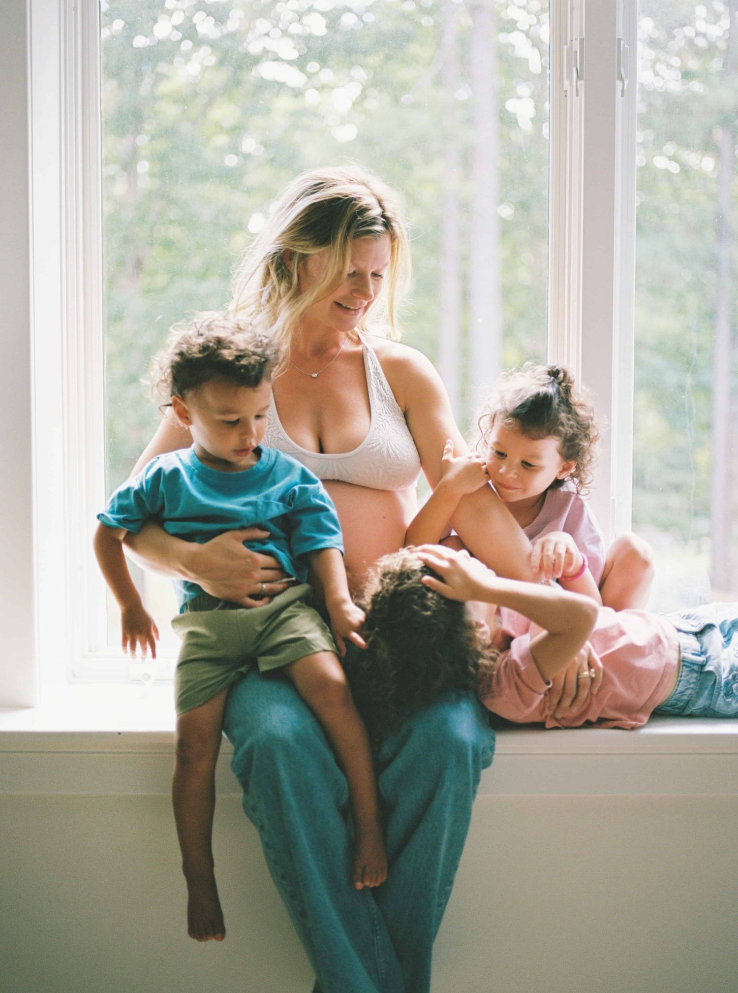 Candid family moment by bright window in casual home setting.