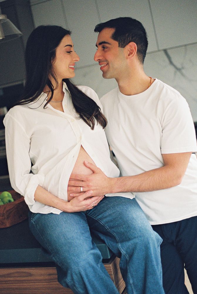 A couple in matching white t-shirts and jeans sit close together sharing intimate moments in a progression of photos.