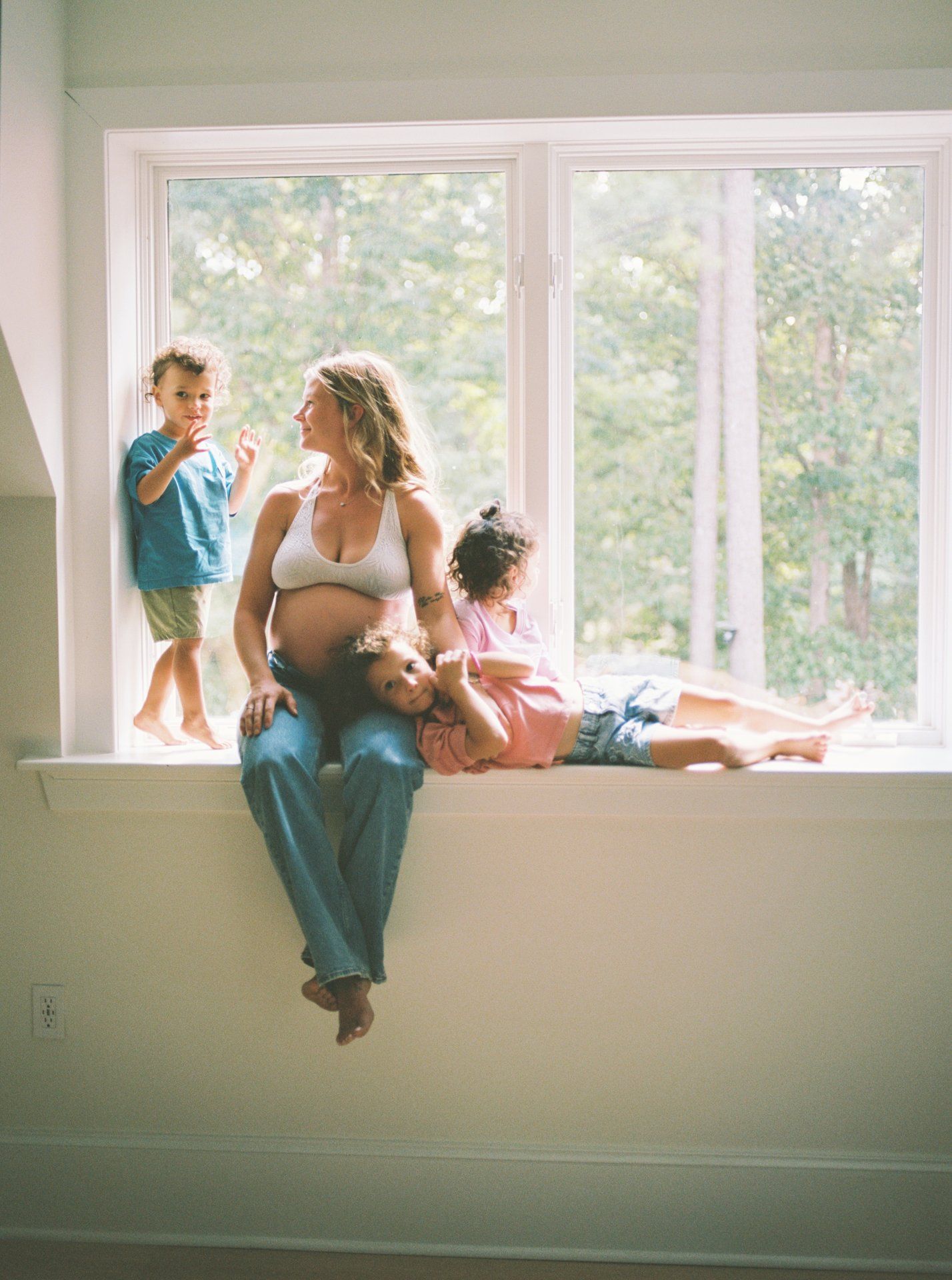 A family sits together on a windowsill in a bright sunlit room creating an intimate moment of connection.