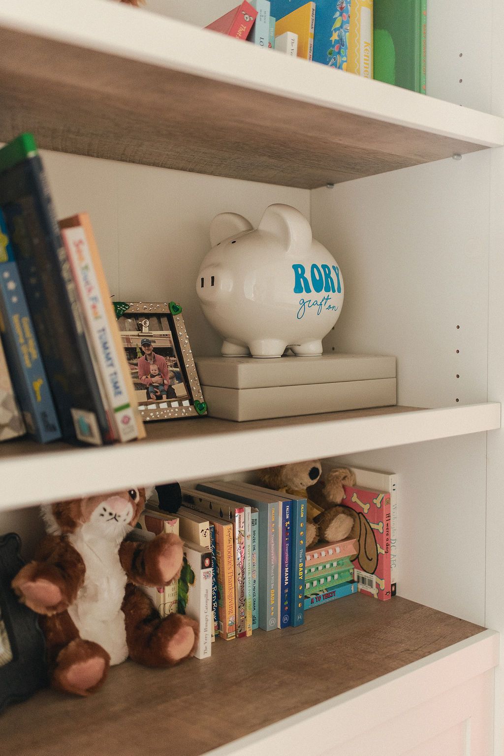 White wooden bookshelves displaying children's books and stuffed animal toys arranged neatly on multiple levels.