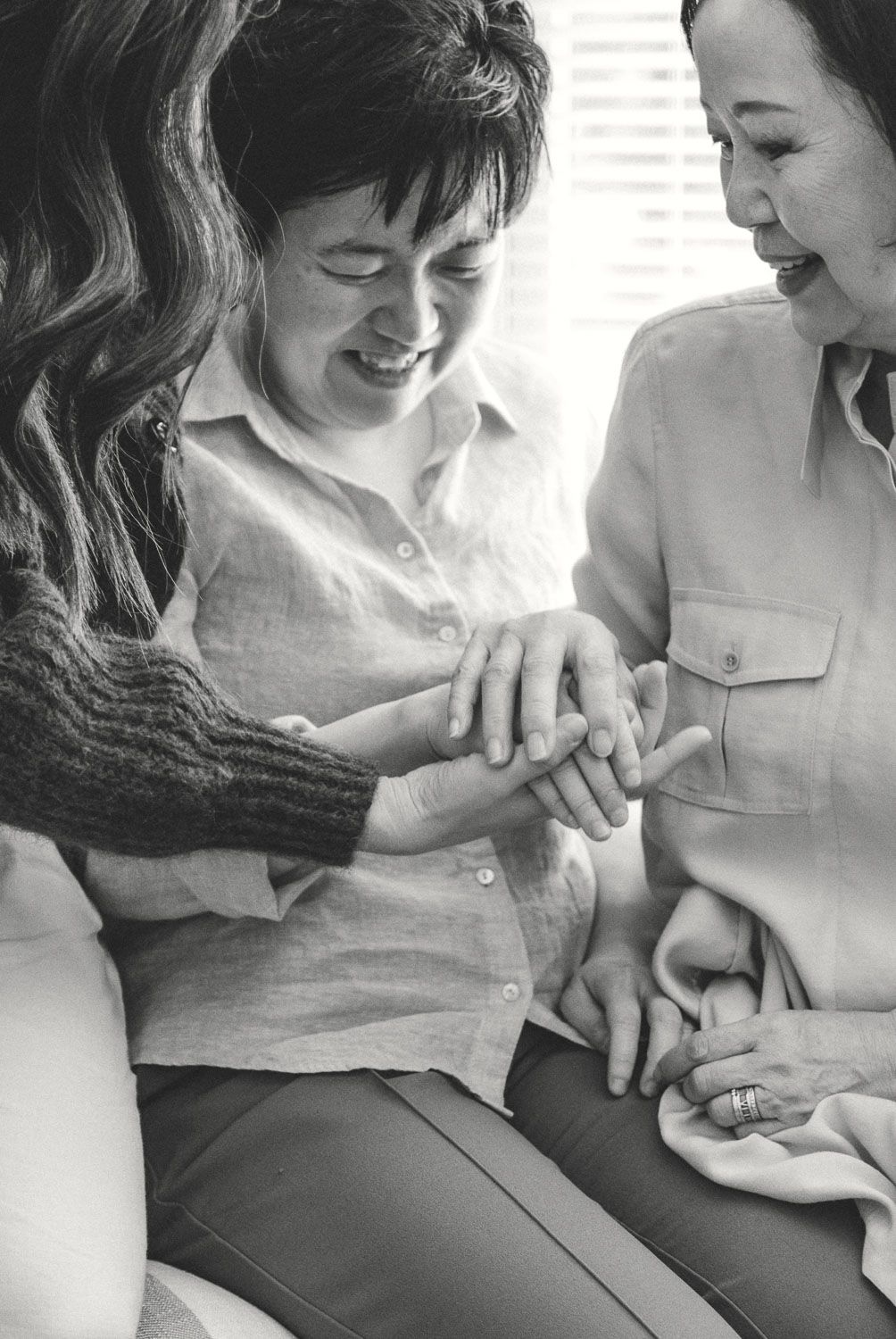 Two women smiling and examining a ring together in a warm, intimate black and white photo.