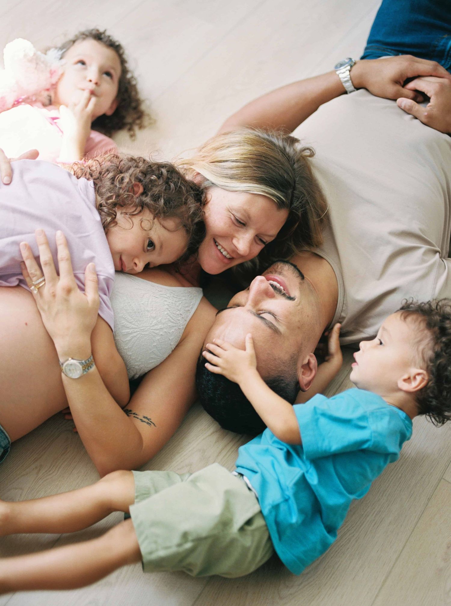 A candid lifestyle photo of family members laying together on a light colored floor.