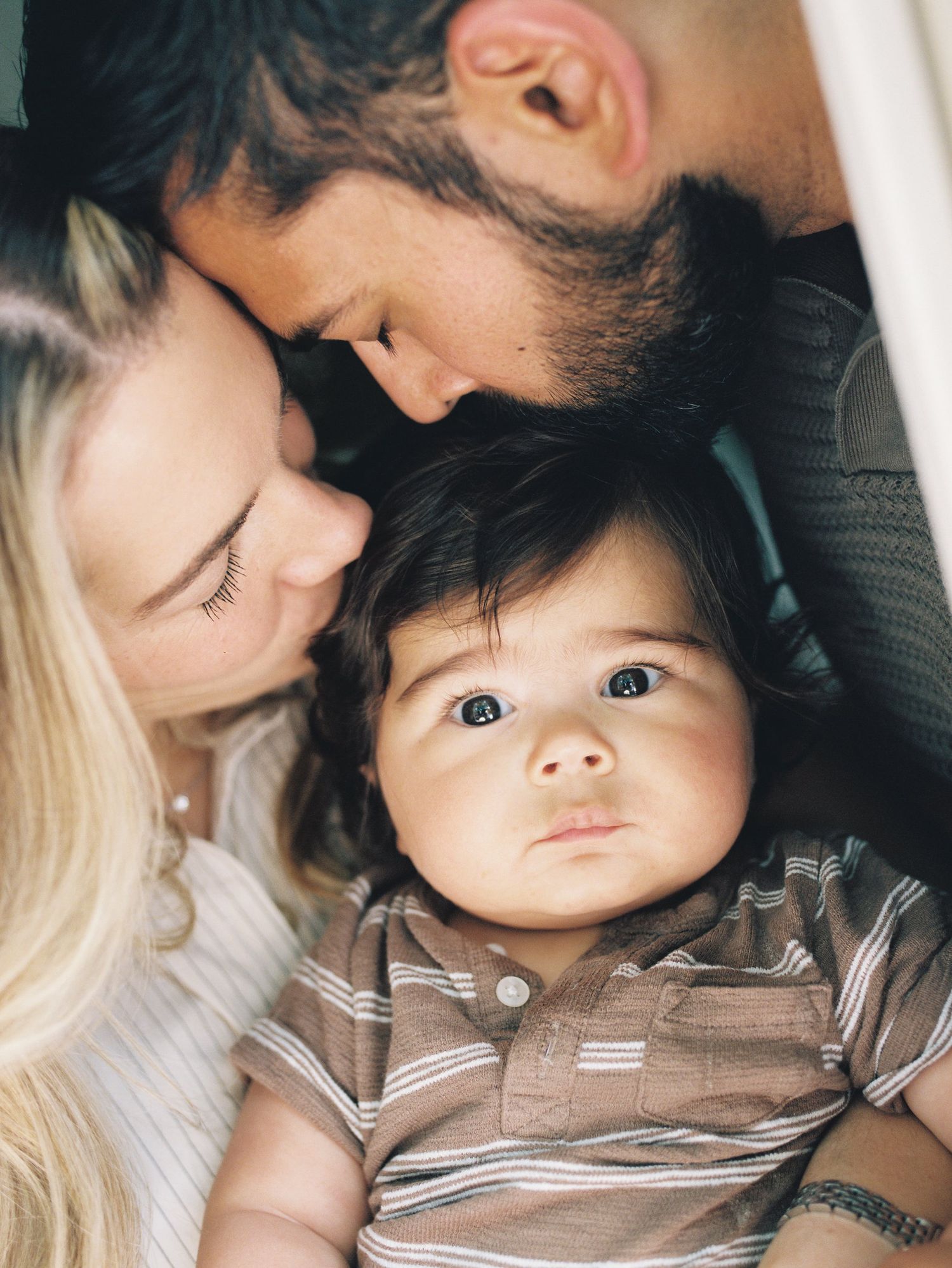 A tender and intimate moment shows parent lying down with a small child wearing a striped shirt.