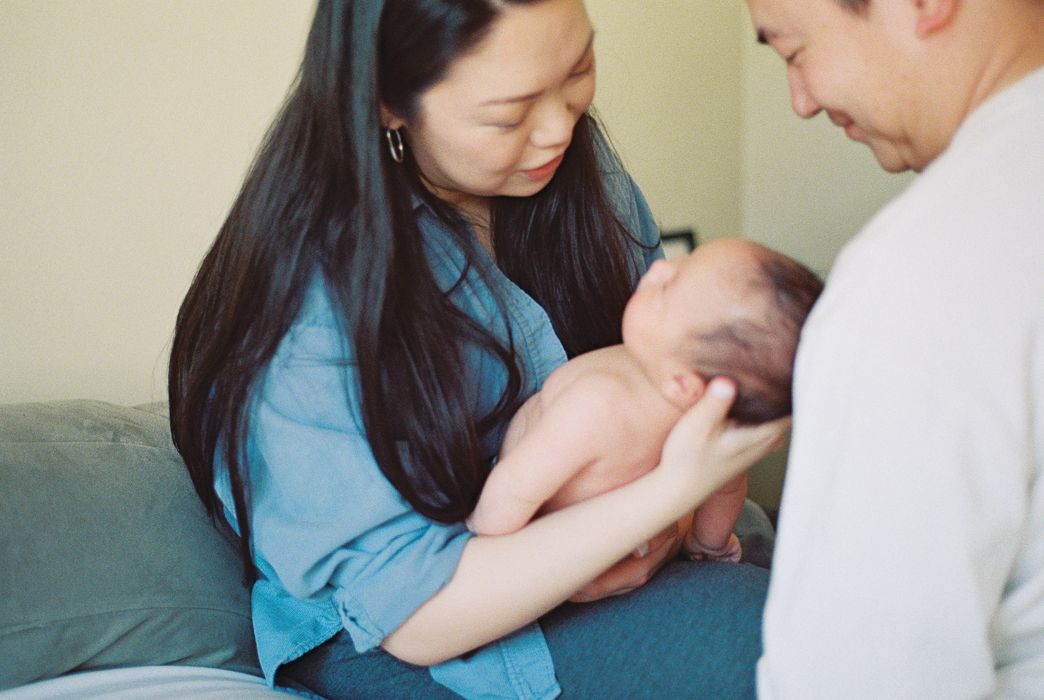 Parents admiring their newborn baby, mother holding infant in arms during a tender family moment.
