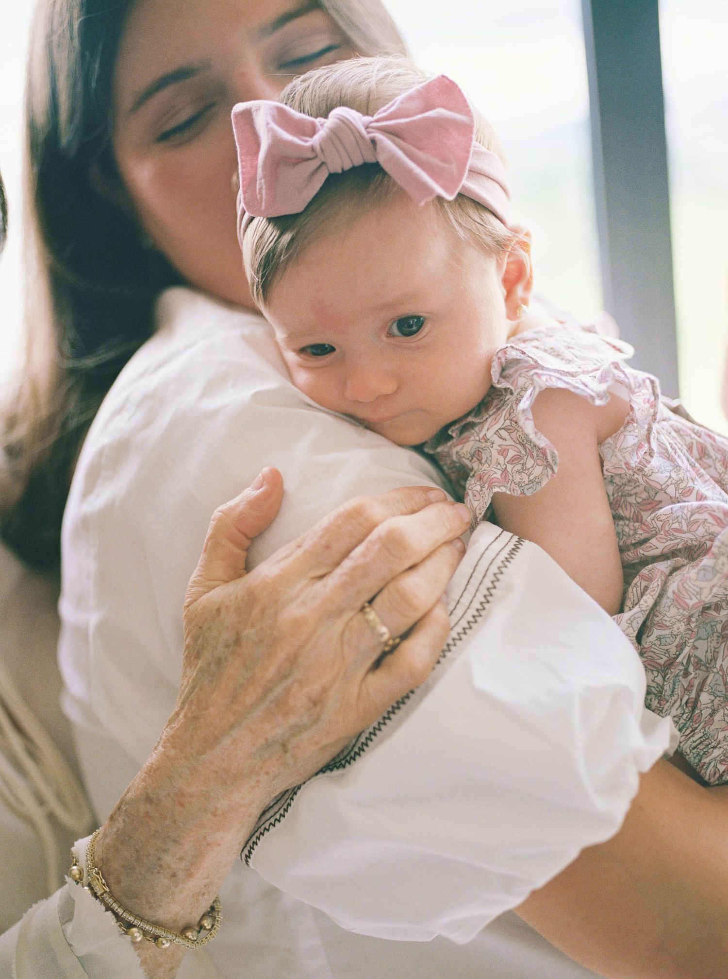 A tender moment captured in a series of intimate photos showing a parent cradling a baby wearing a pink bow.