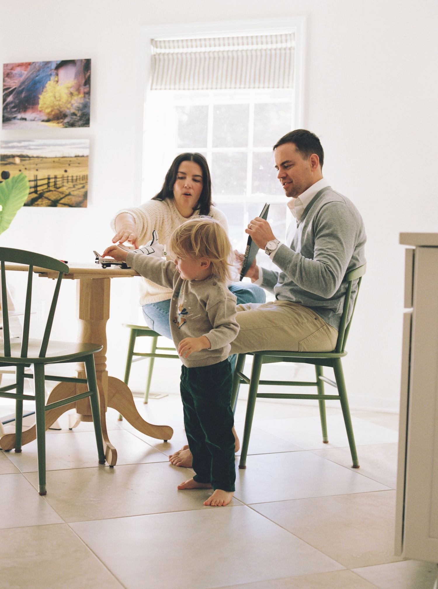 A group of people relaxing and using mobile devices while sitting on chairs in a bright, modern interior space.