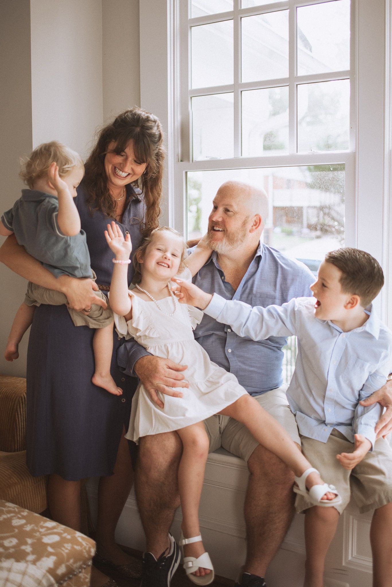 A family shares joyful moments together by the window in a series of candid lifestyle photos.