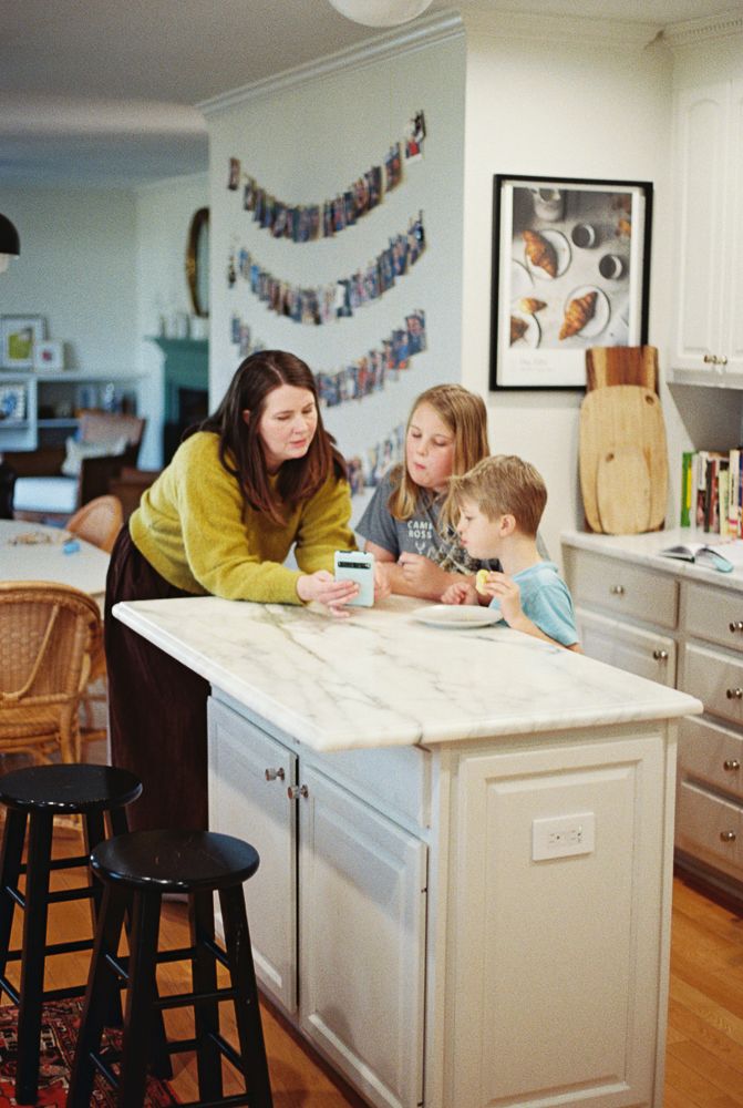 Family gathered around kitchen counter for homework and activities in bright modern kitchen space.