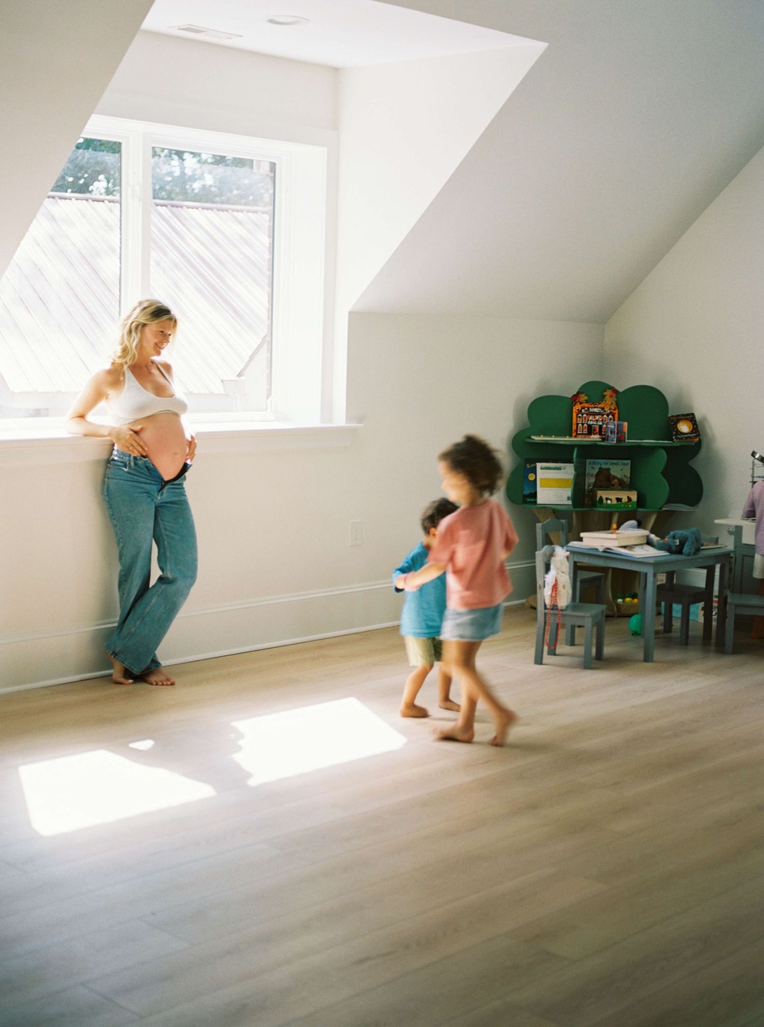 Children playing in a bright sunlit attic room with wooden floors.