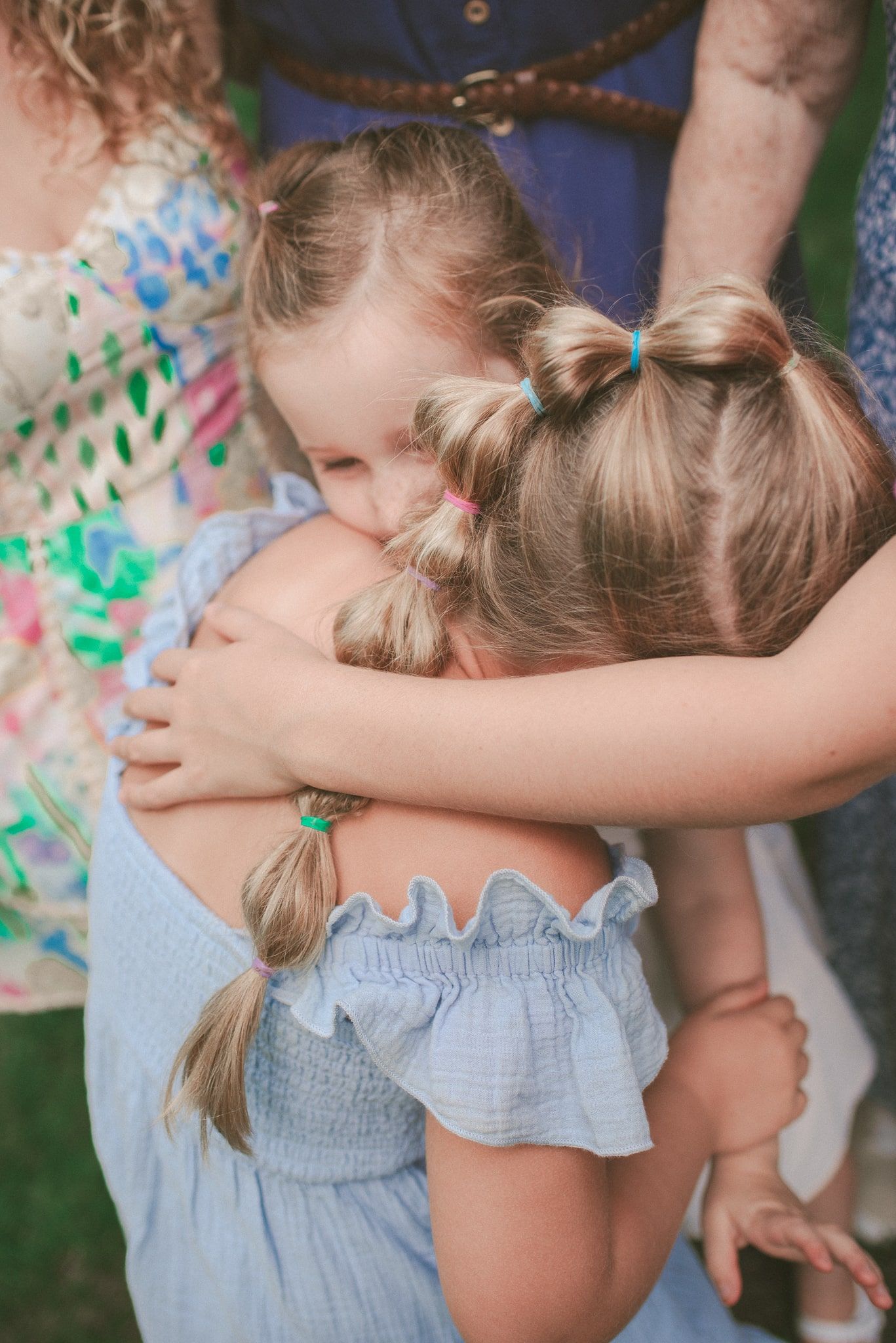 Two children share a tender embrace while wearing light summer clothing outdoors.