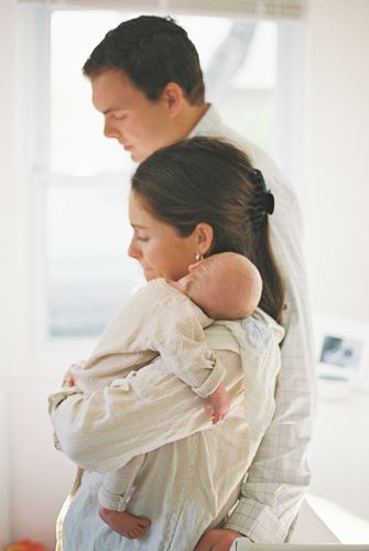 A couple lovingly gazes down at their newborn baby, with the mother cradling the infant gently in her arms.