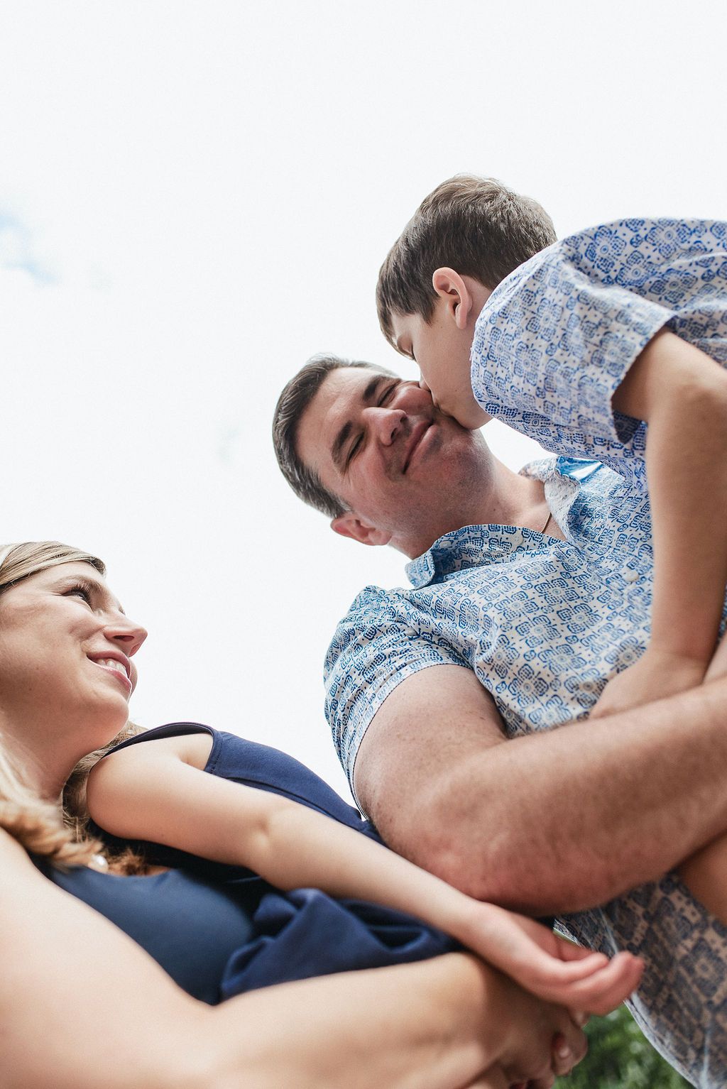 A couple shares a tender moment together while lying down outdoors on a sunny day.