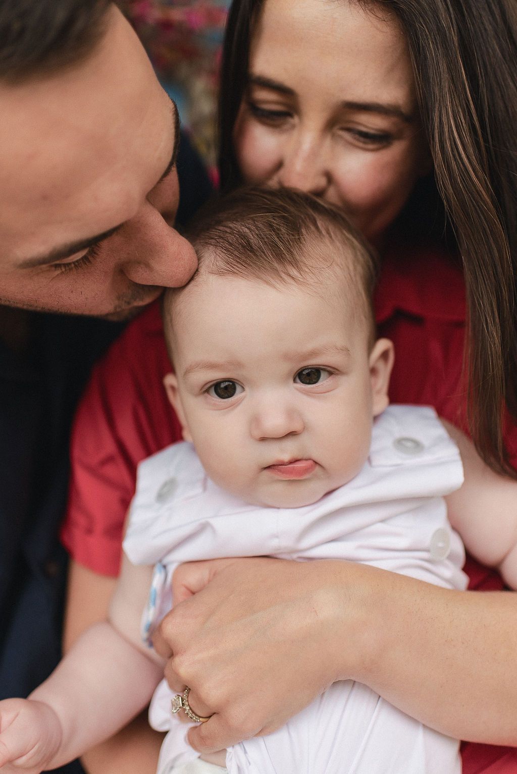 A baby in a white onesie shares tender moments while being held in multiple candid shots.