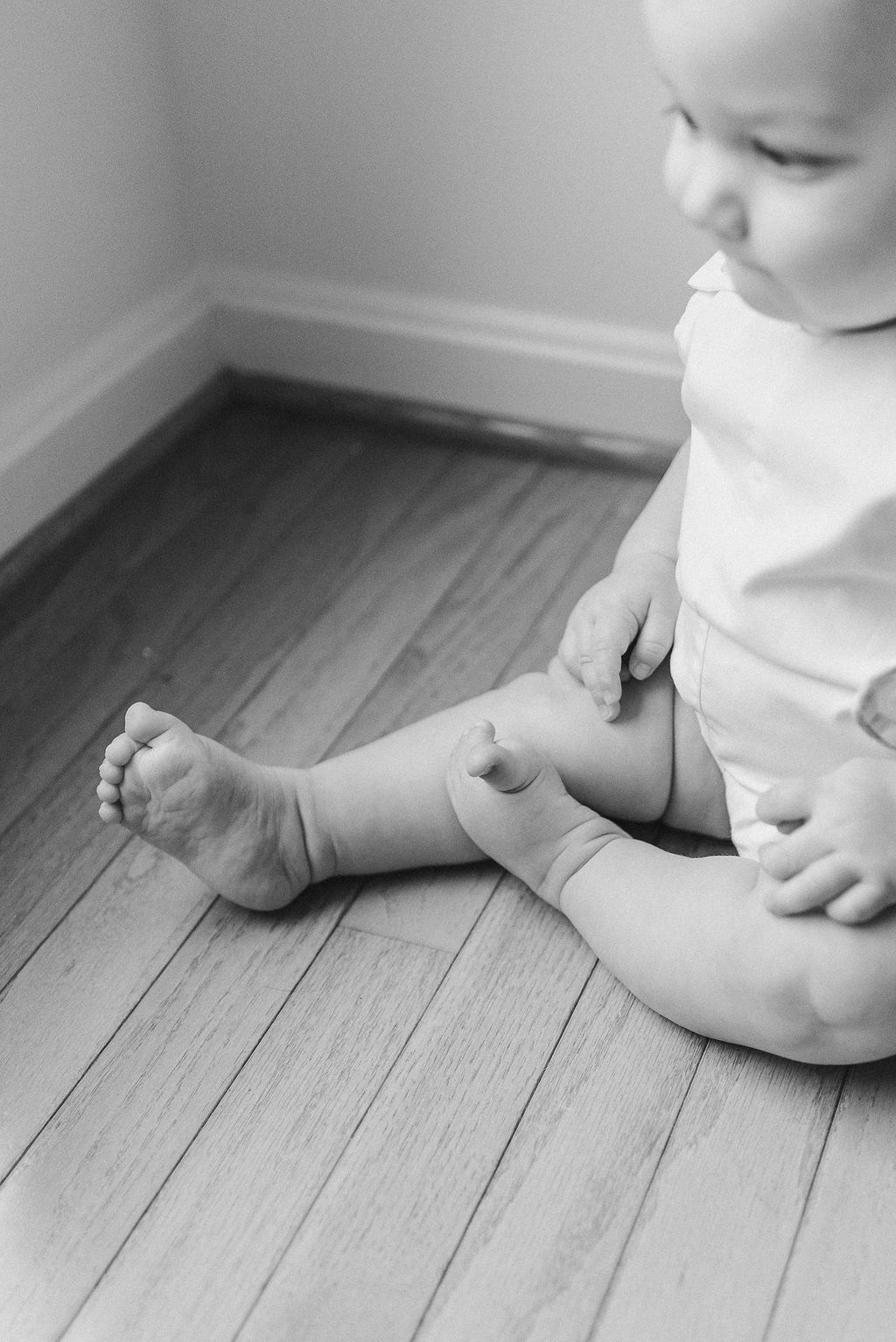 Close-up series of tiny baby feet on hardwood flooring in black and white.