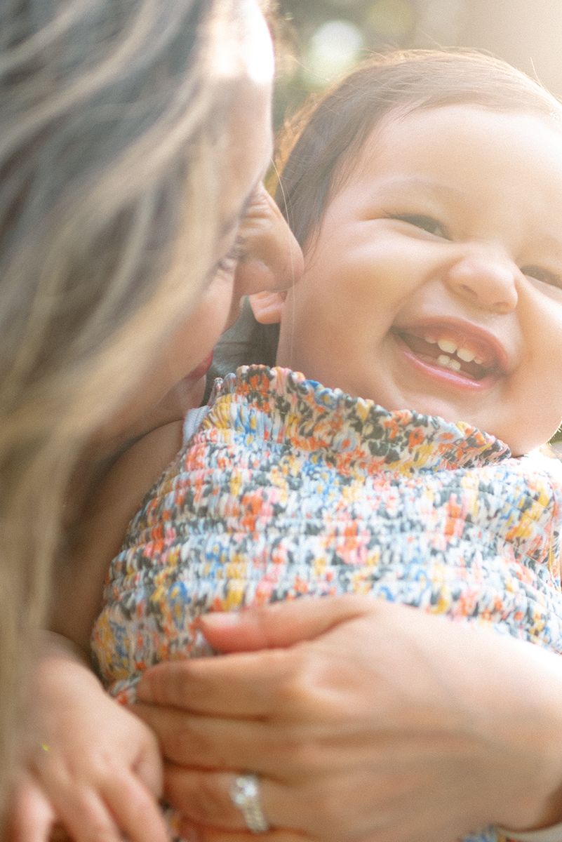 A joyful moment captured in soft sunlight showing pure happiness and a colorful floral patterned dress.