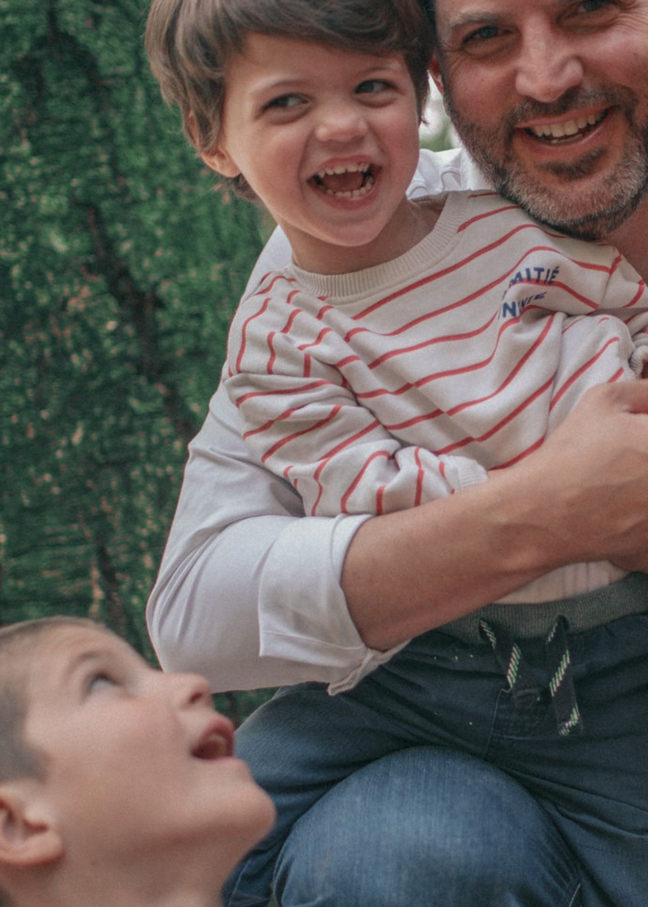 A playful series of candid outdoor portraits showing joyful laughter and warm embraces against a green background.