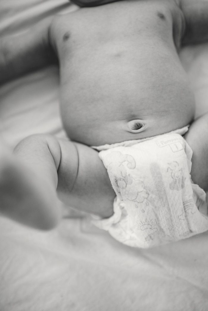 Black and white close-up photo of a newborn baby lying on a blanket wearing a diaper.