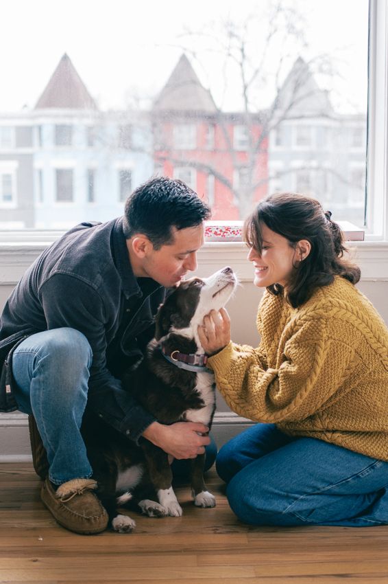 A couple sits on the floor with their dog in a series of playful poses by a window.