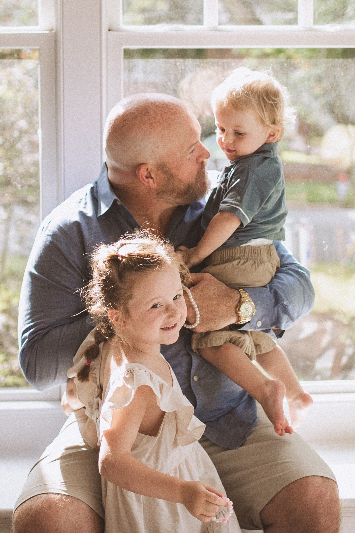 Heartwarming family moments captured in a sunlit room with natural window lighting in the background.