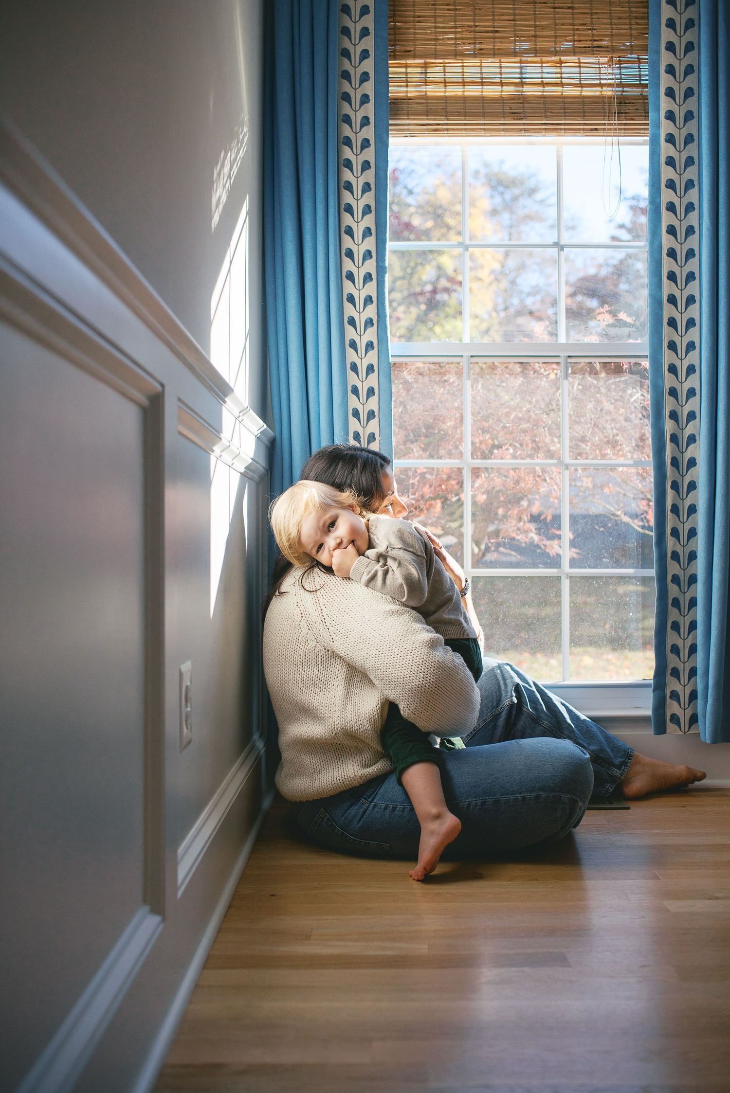 A person lying on a hardwood floor against a white wall with large windows in a sequence of relaxed poses.