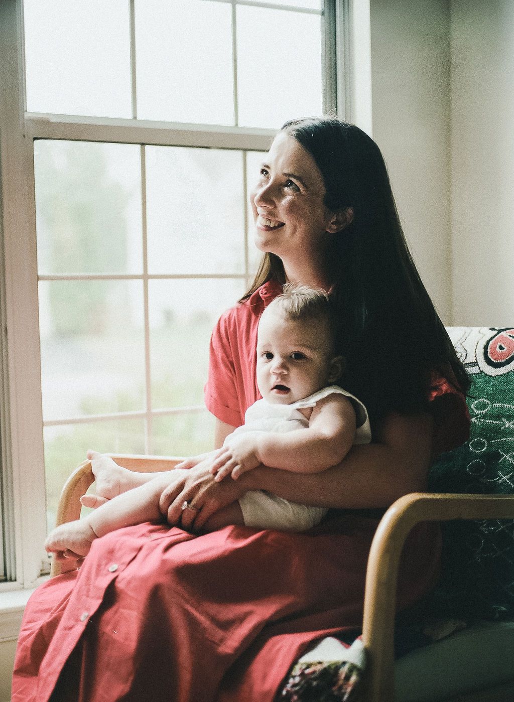 Intimate family moment captured by window light showing tenderness and connection.