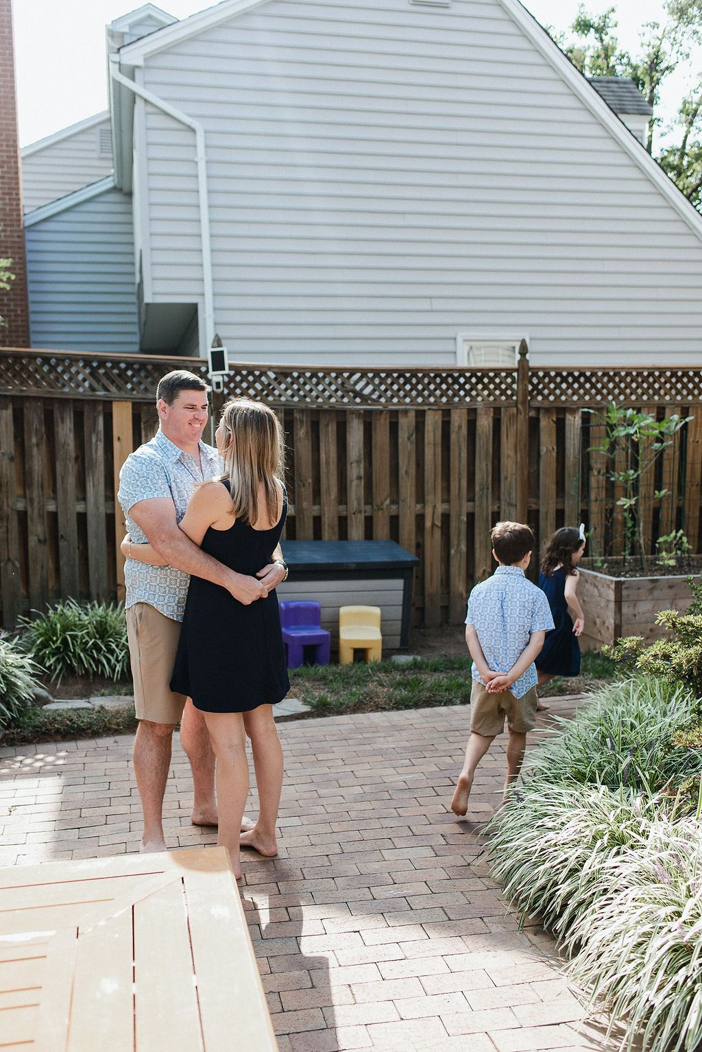 A series of playful moments captured on a brick patio with a white house and wooden fence in the background.